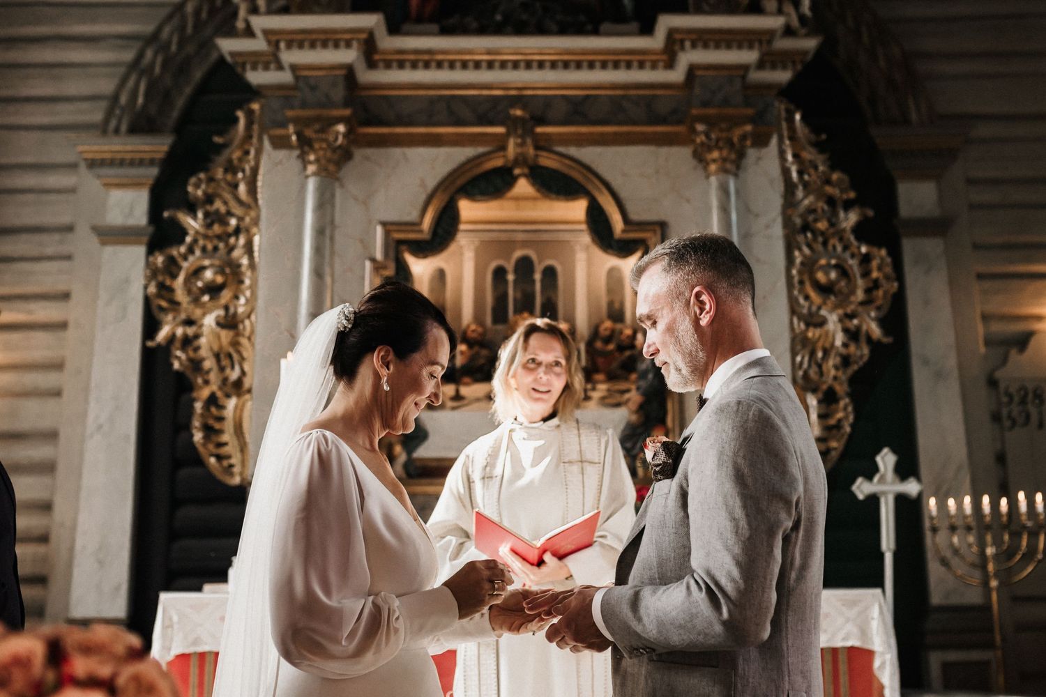 A traditional church wedding ceremony takes place beneath ornate golden decorative elements.