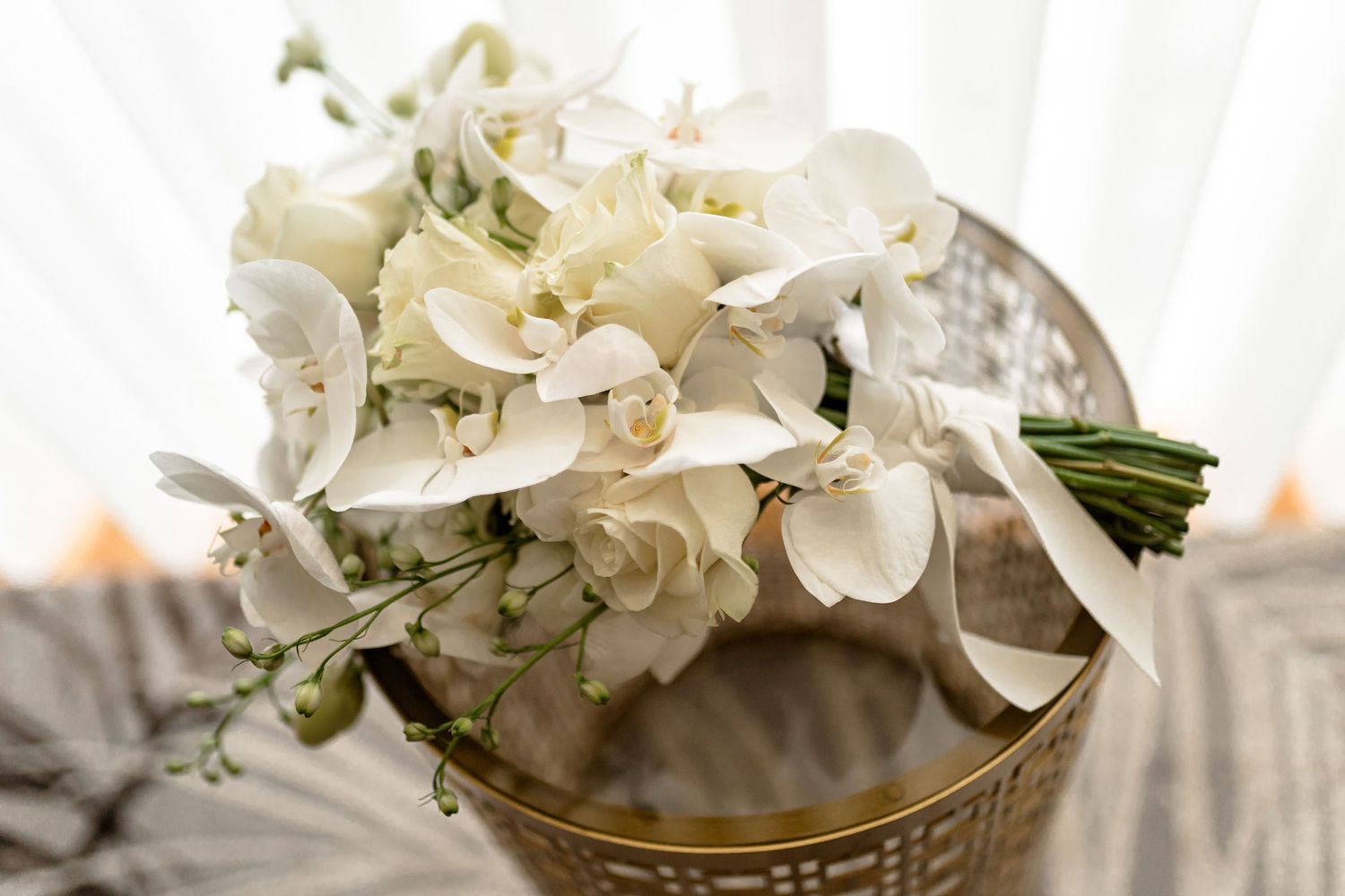 White hydrangea wedding bouquet arranged with delicate flowers and greenery against a light background.