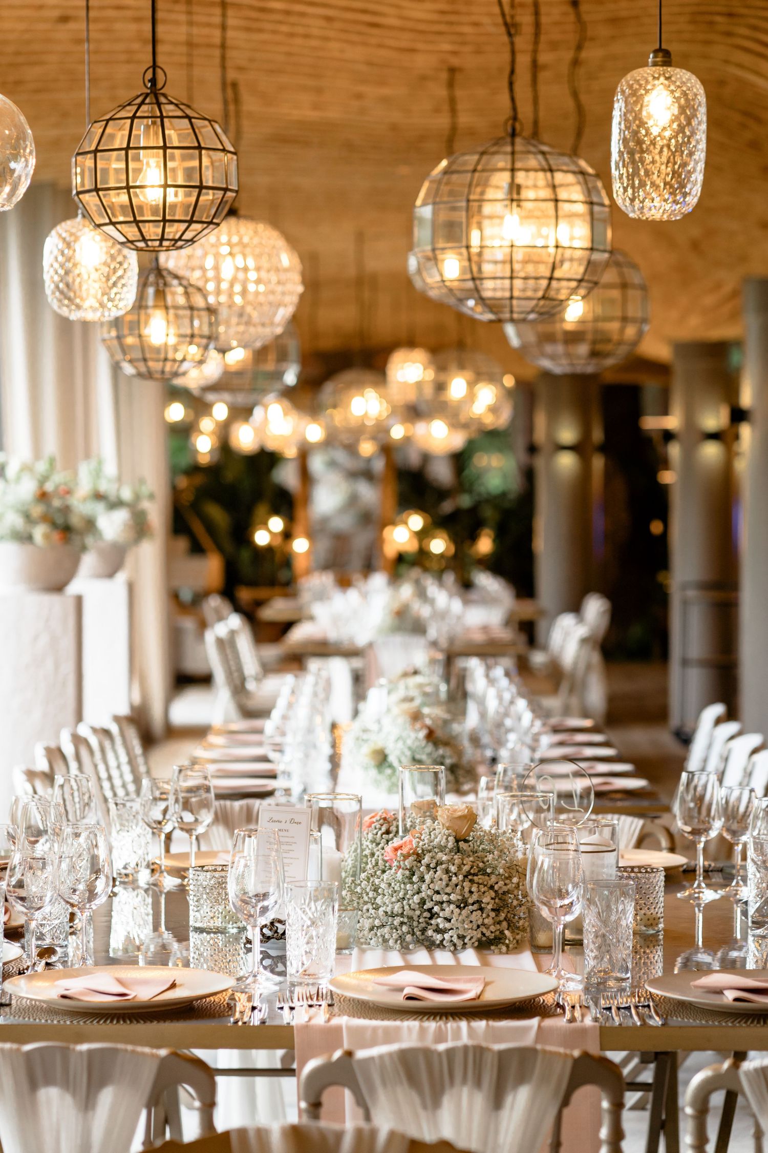 Wedding reception venue with hanging crystal chandeliers and elegant table settings.
