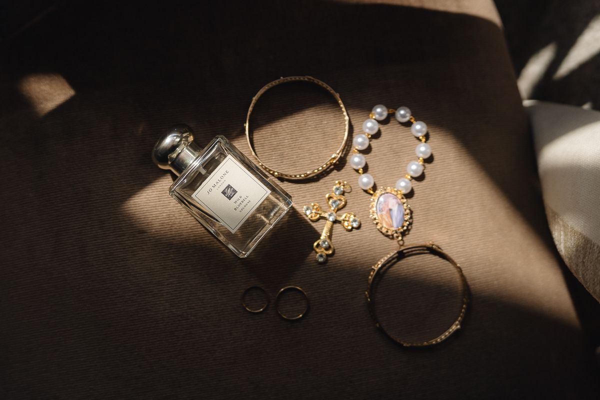 Wedding accessories including jewelry and rings arranged in dramatic lighting.