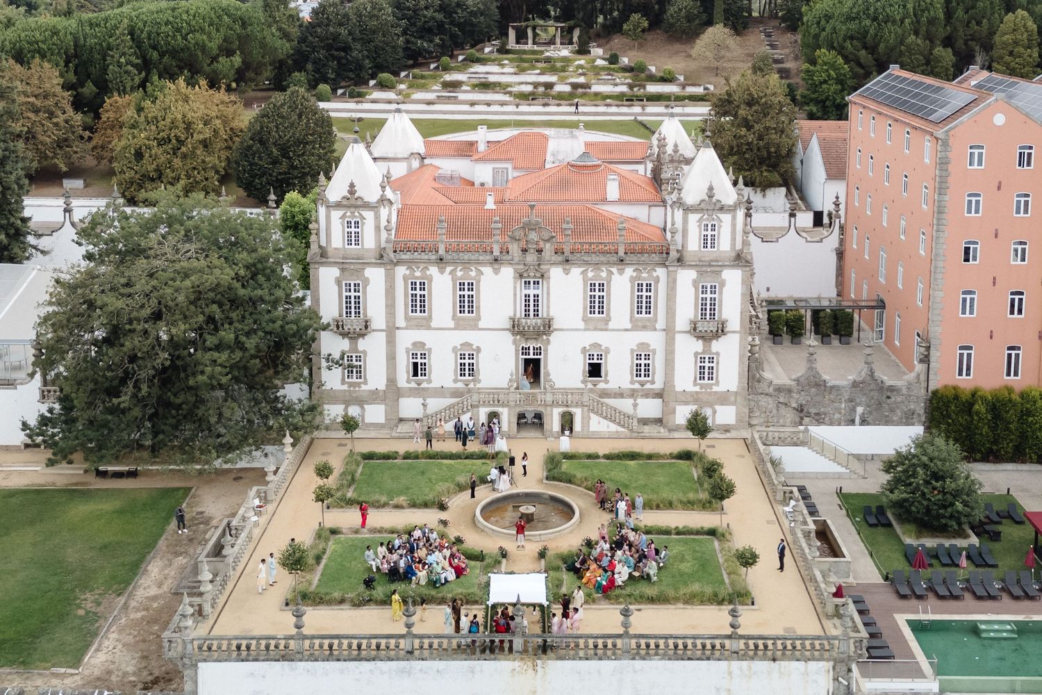 Aerial view of a grand European palace and its manicured gardens with formal landscaping.