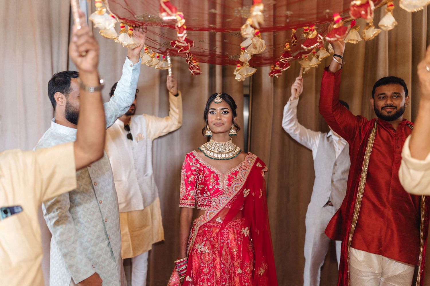 Wedding celebration with guests dancing and celebrating in traditional red and white formal attire.
