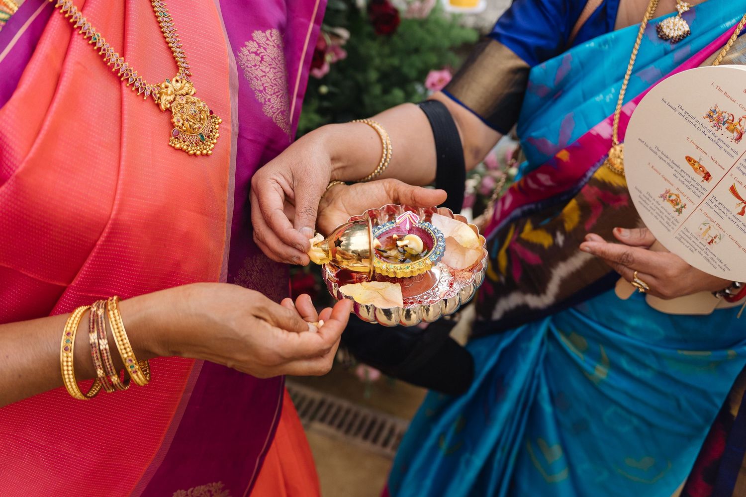 Colorful hands holding traditional Indian wedding accessories and jewelry.