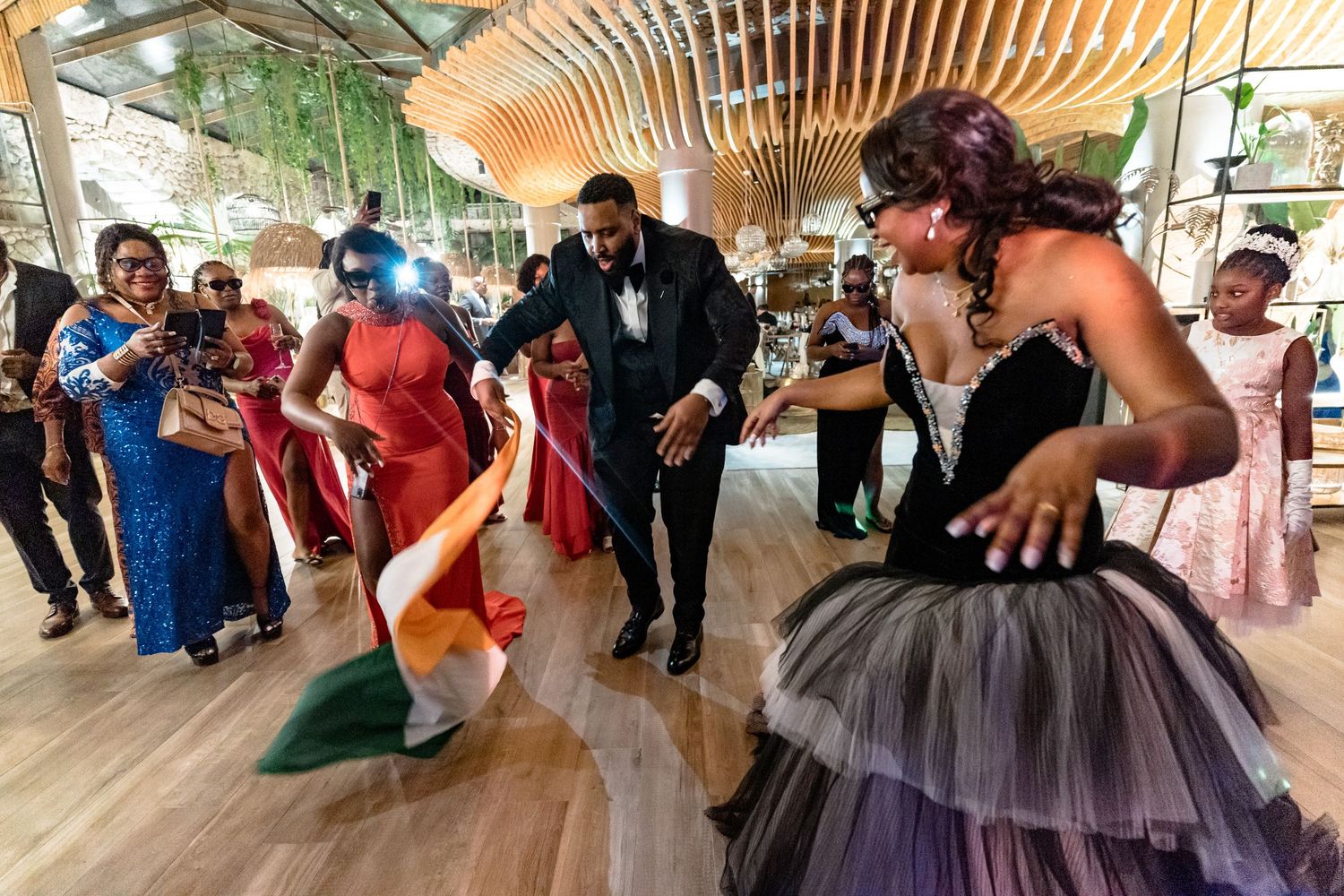 Partygoers dancing beneath a wooden slatted ceiling at an elegant outdoor venue.