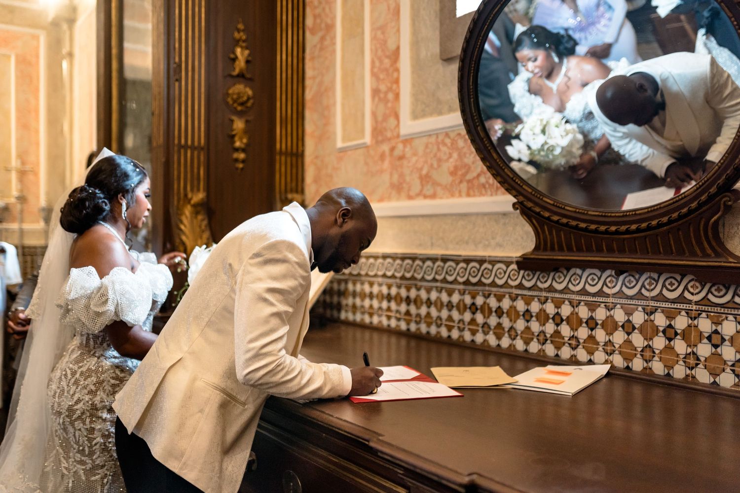 A couple signs their marriage documents in an elegant church interior.