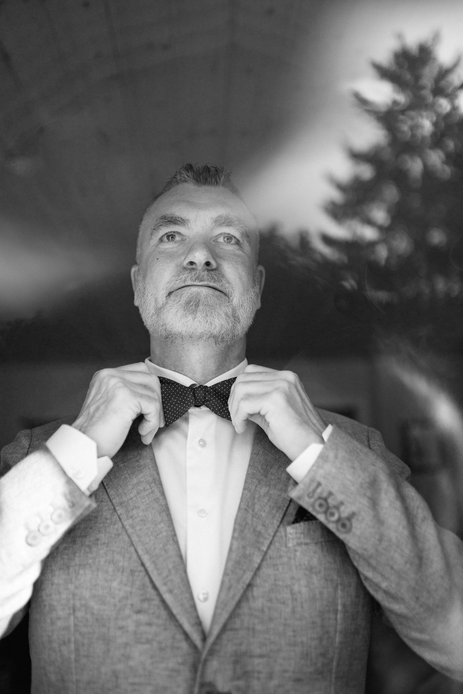 Black and white sequence of a groom adjusting his bowtie and collar before the wedding ceremony.