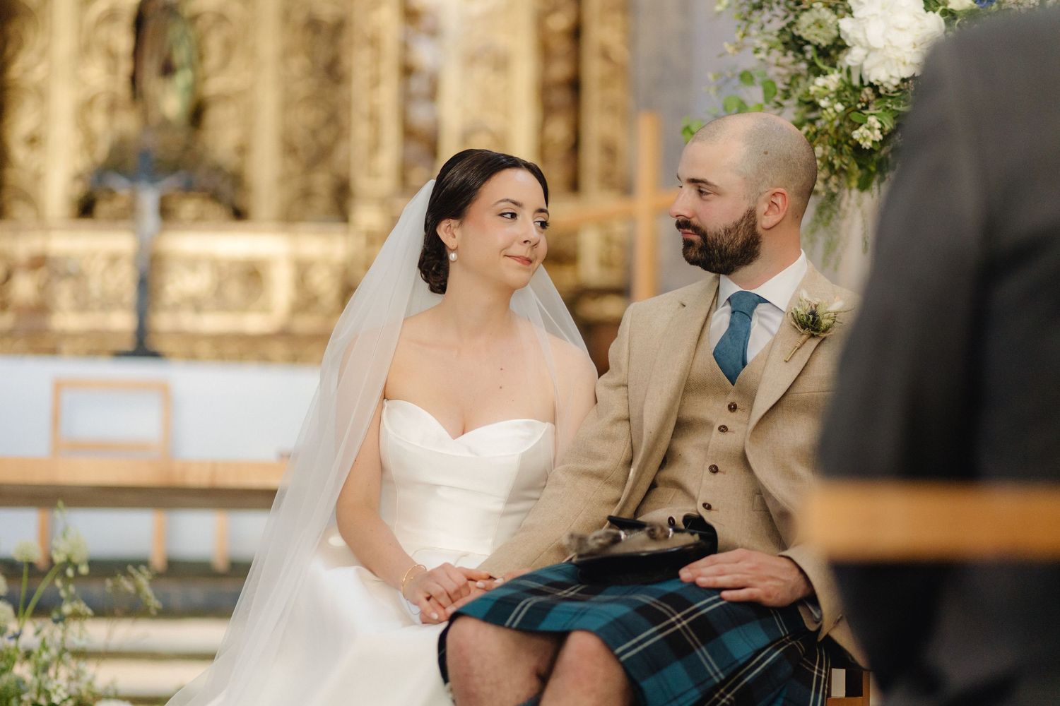Romantic wedding ceremony in a historic chapel with white floral decorations.