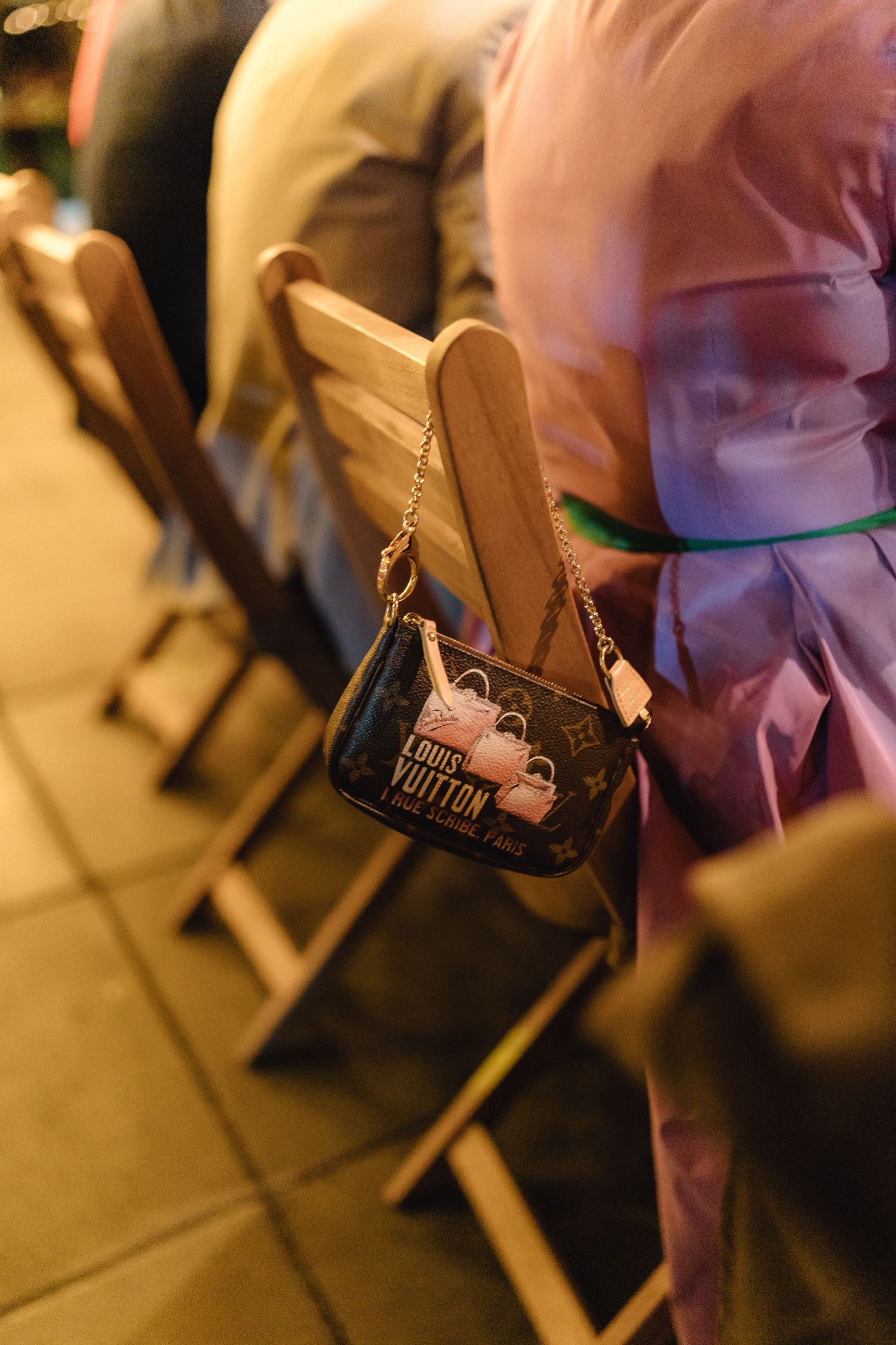 Row of wooden chairs with handbags at an evening reception venue.