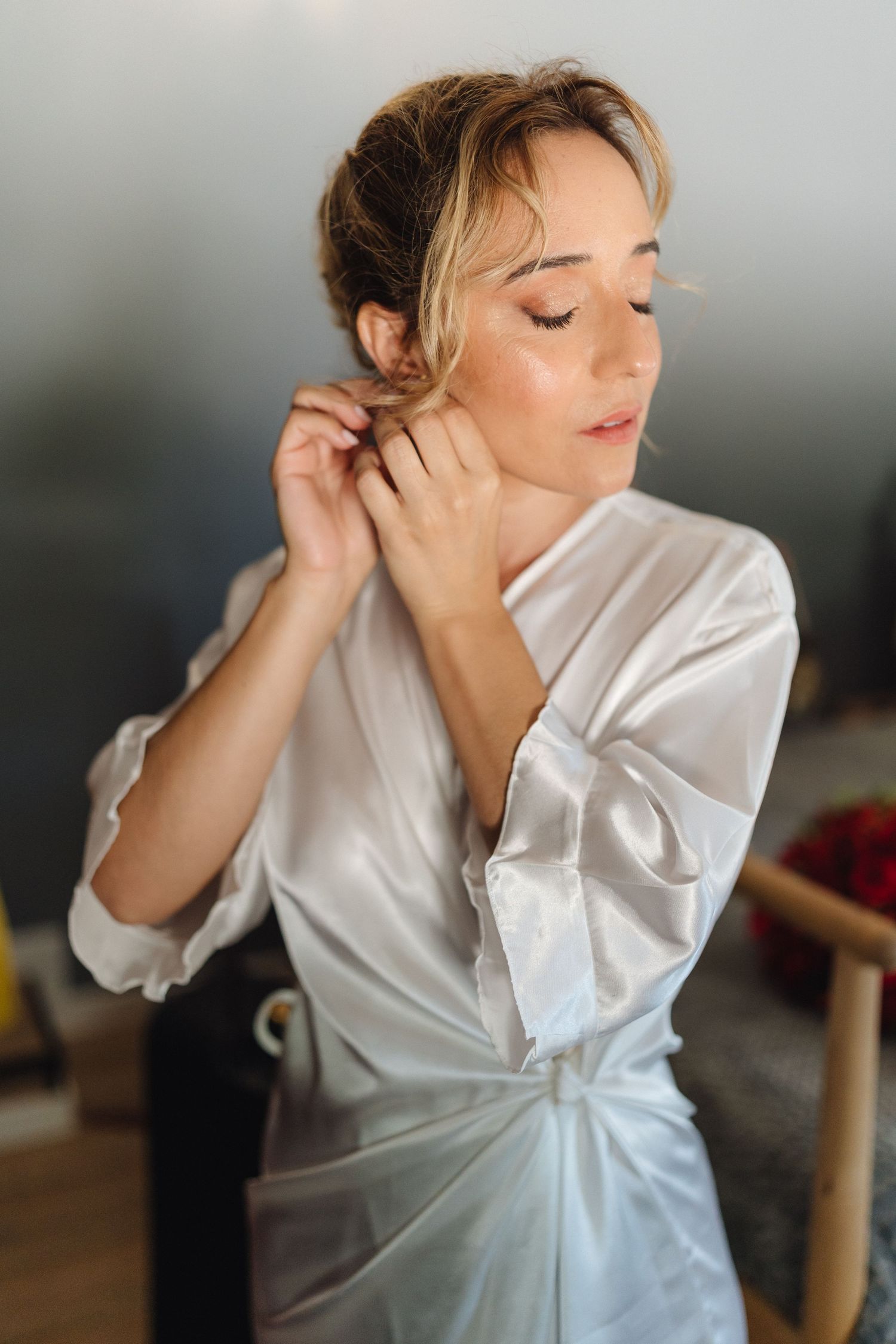 Elegant portrait of someone in white wrapped dress with soft lighting and natural makeup.