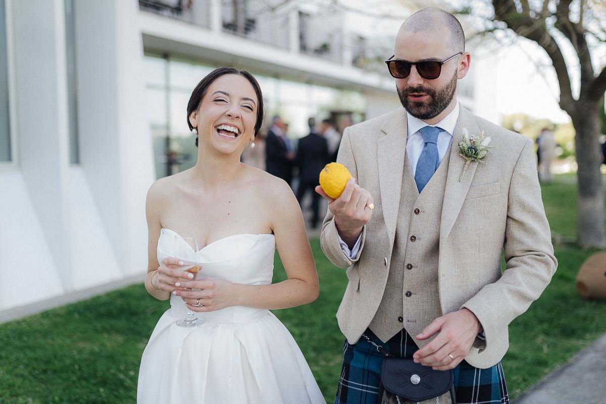 A joyful couple laughs together during their outdoor wedding celebration.