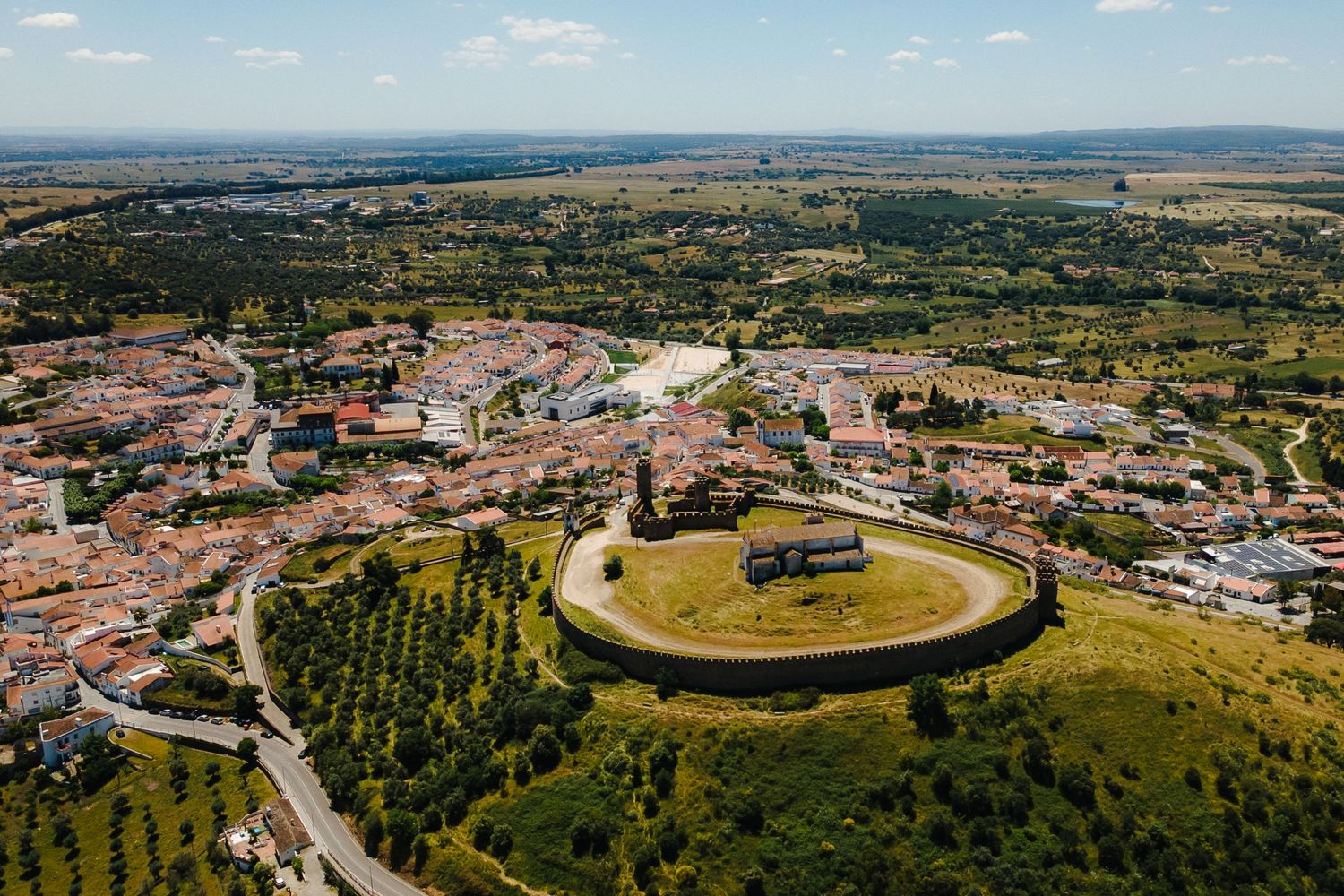 Aerial panoramic view of a historic bullring arena and surrounding town in Spain.