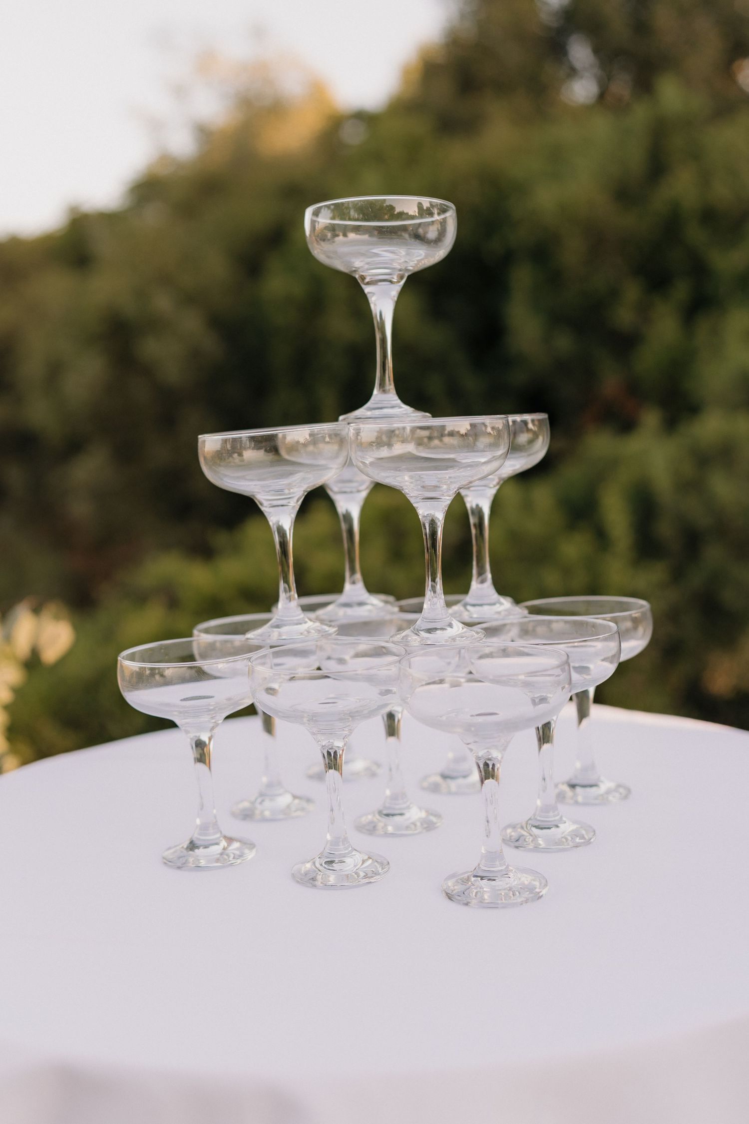 Empty champagne glasses arranged in rows on a white tablecloth for a wedding celebration.