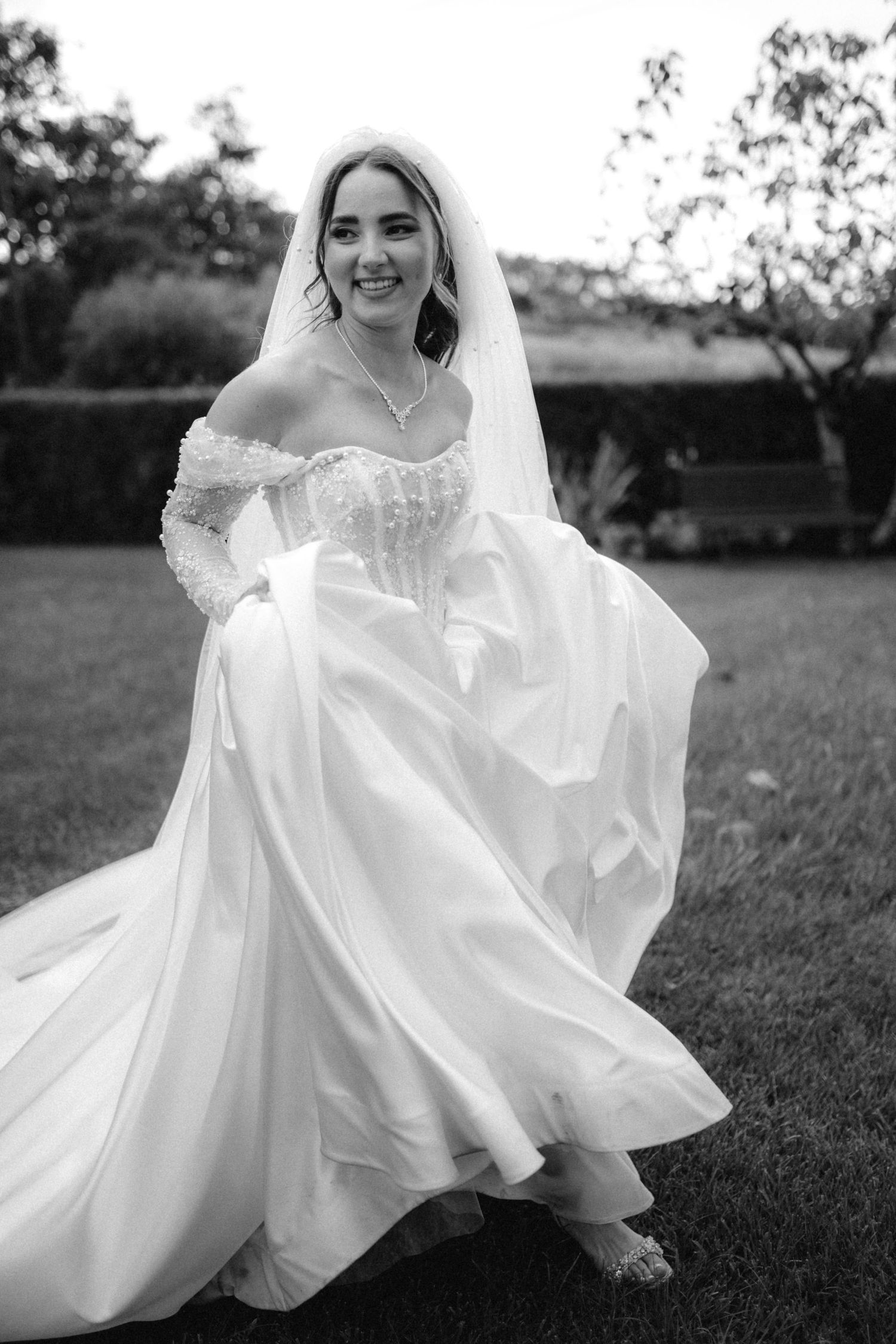 Black and white photo of flowing wedding dress movement in an outdoor setting.