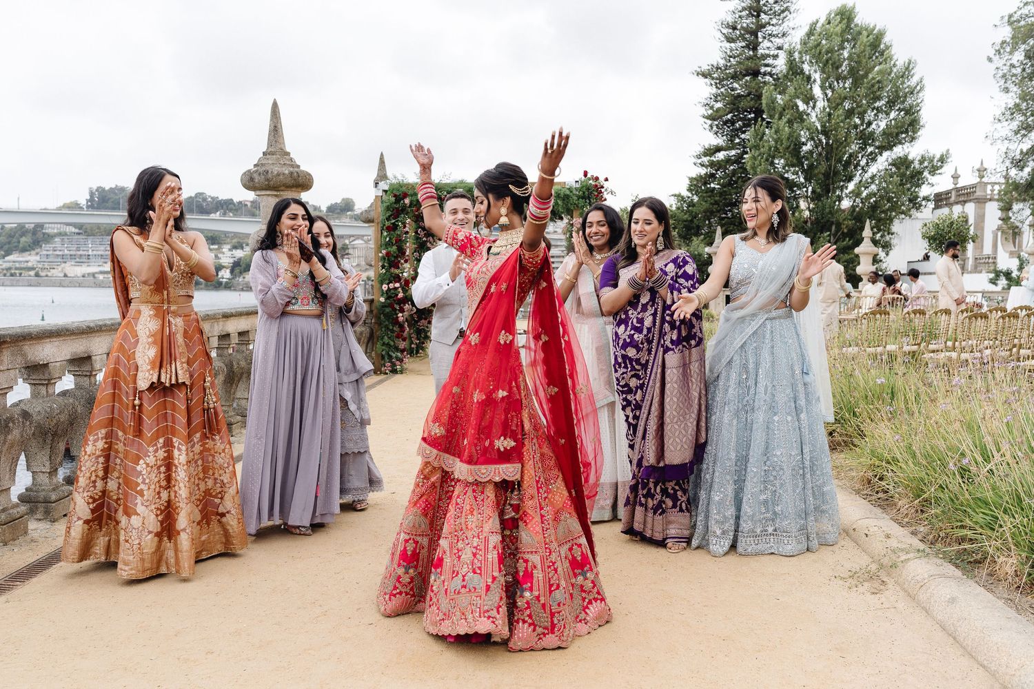 Wedding guests in colorful traditional attire gather for outdoor group photos.