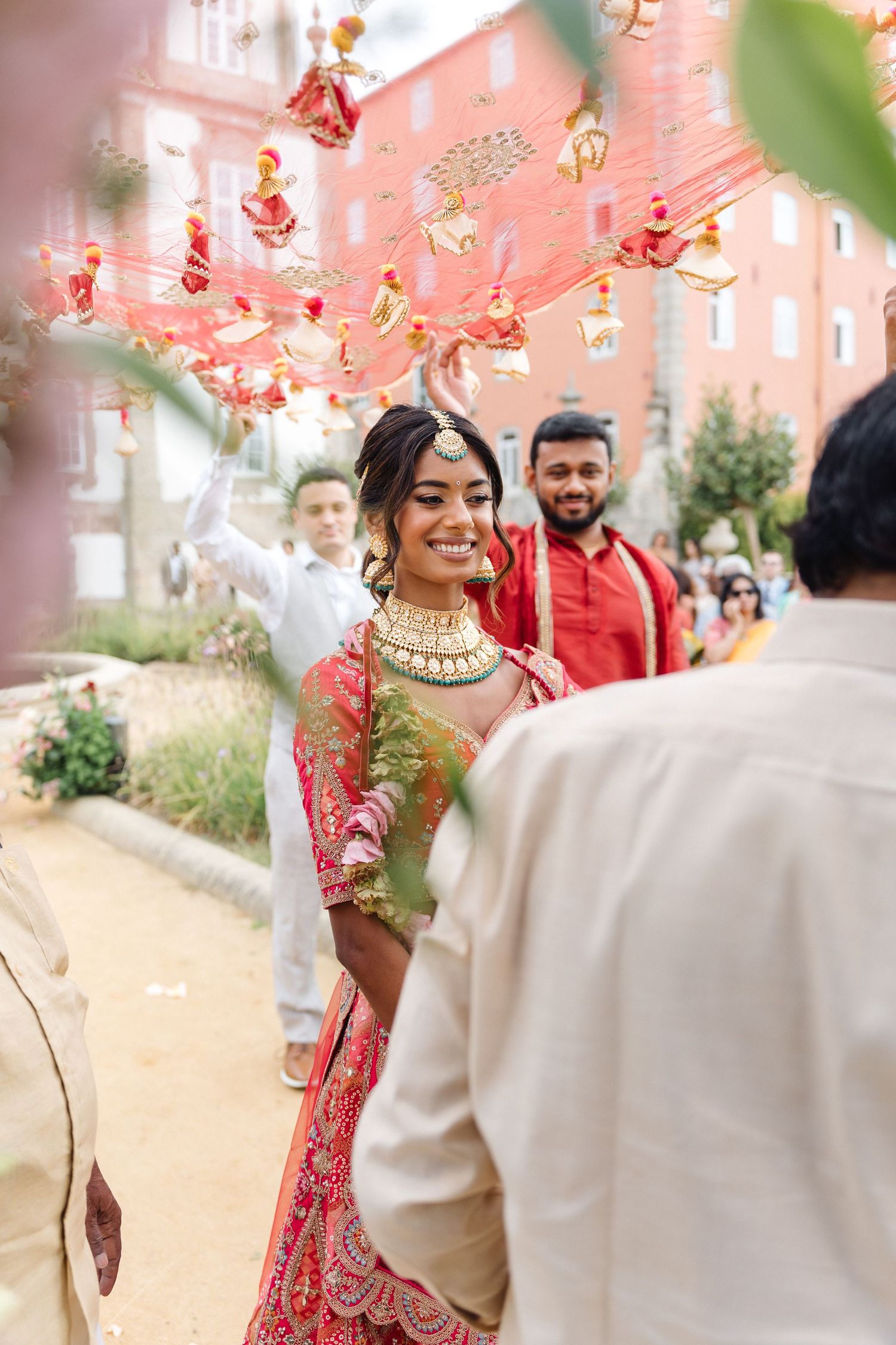Traditional Indian wedding ceremony space decorated with pink and red hanging ornaments.