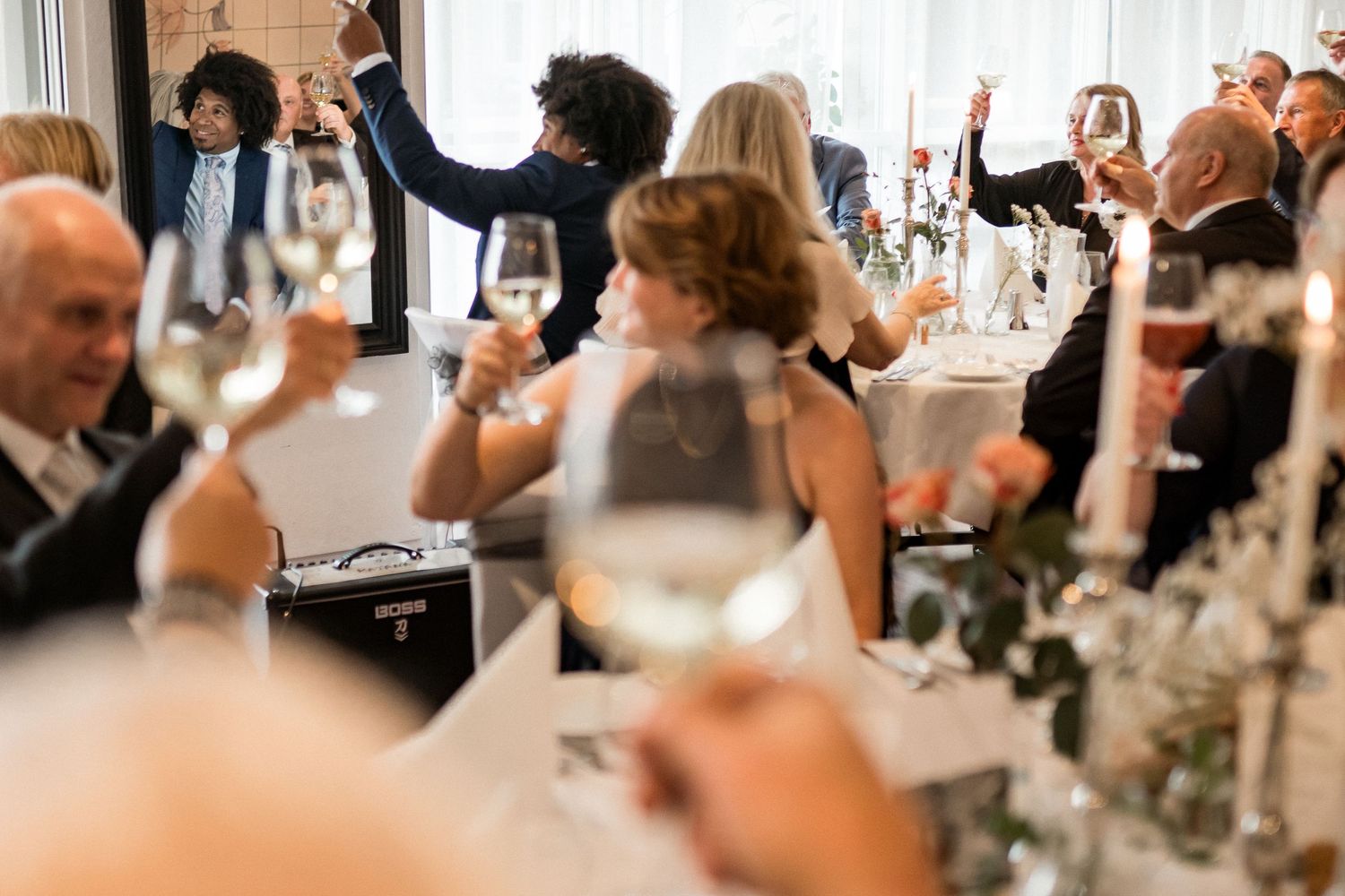 Wedding reception guests celebrating and toasting at decorated tables.