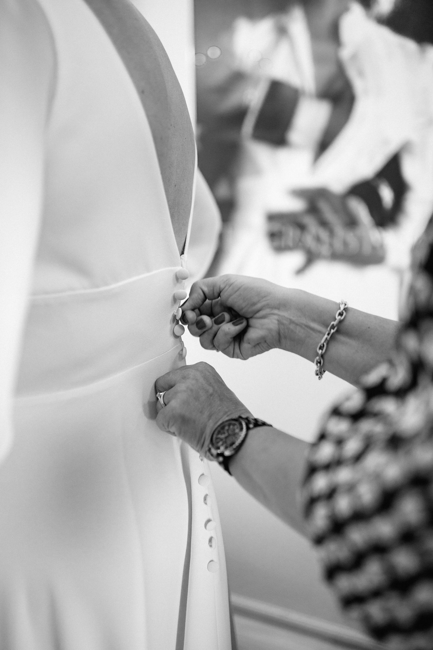 Close-up black and white shot of hands adjusting wedding dress details.