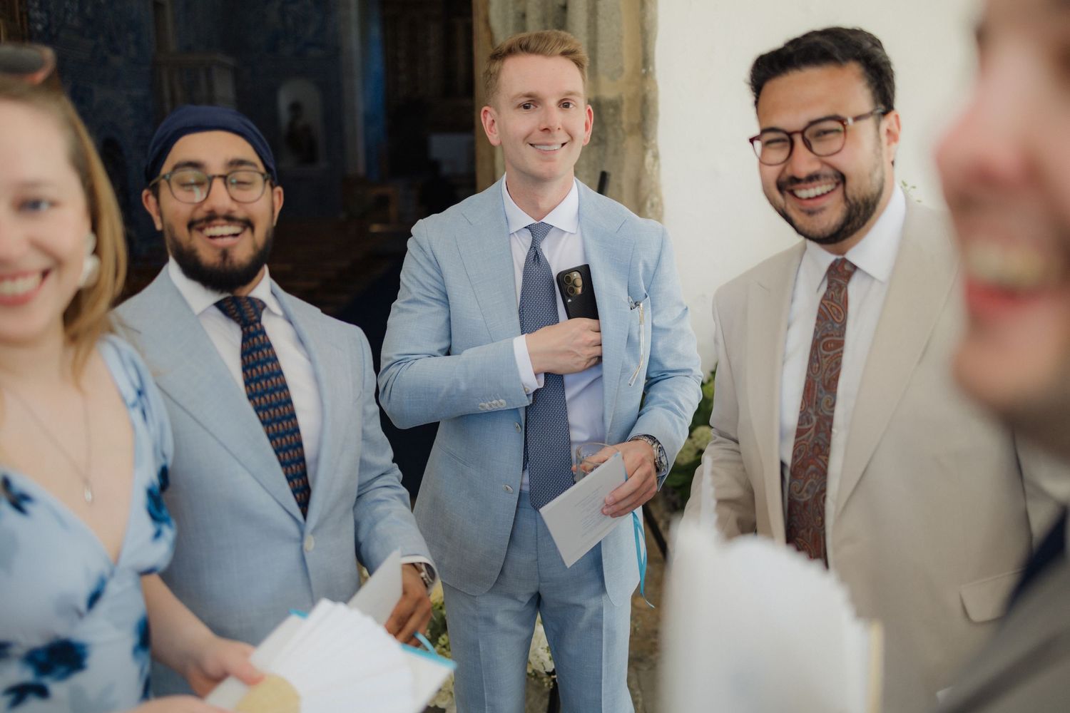 Wedding guests in formal attire mingling and socializing at an indoor venue.