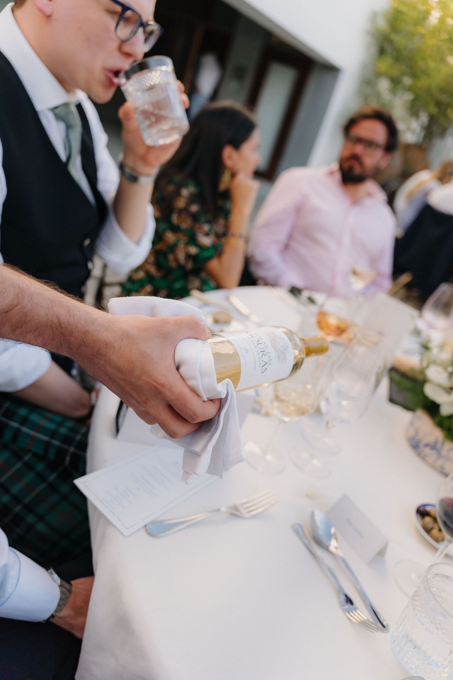 Close-up of table settings and drinks being served at an outdoor wedding reception.