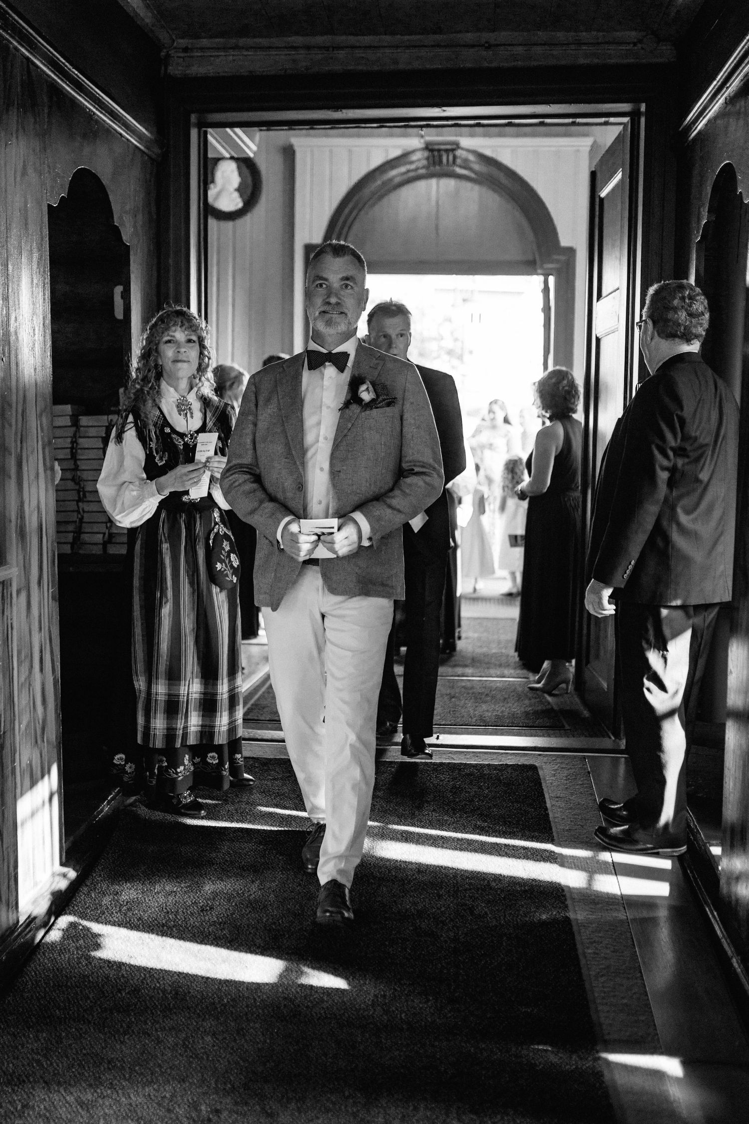 Black and white hallway shots showing wedding guests walking through sunlit corridors.