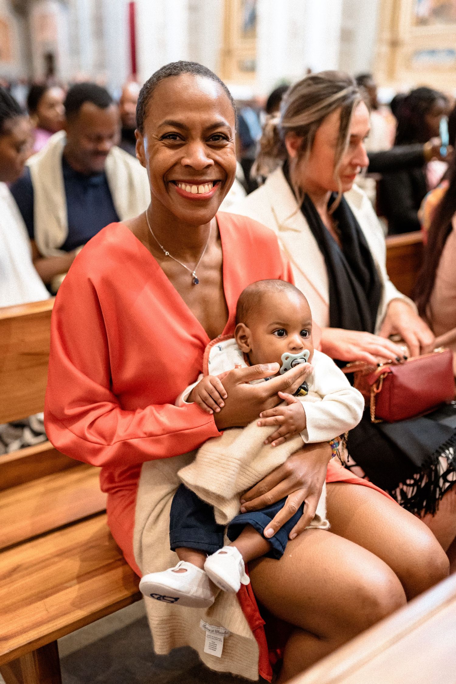 Candid moments of a joyful celebration with a baby in coral-colored attire.