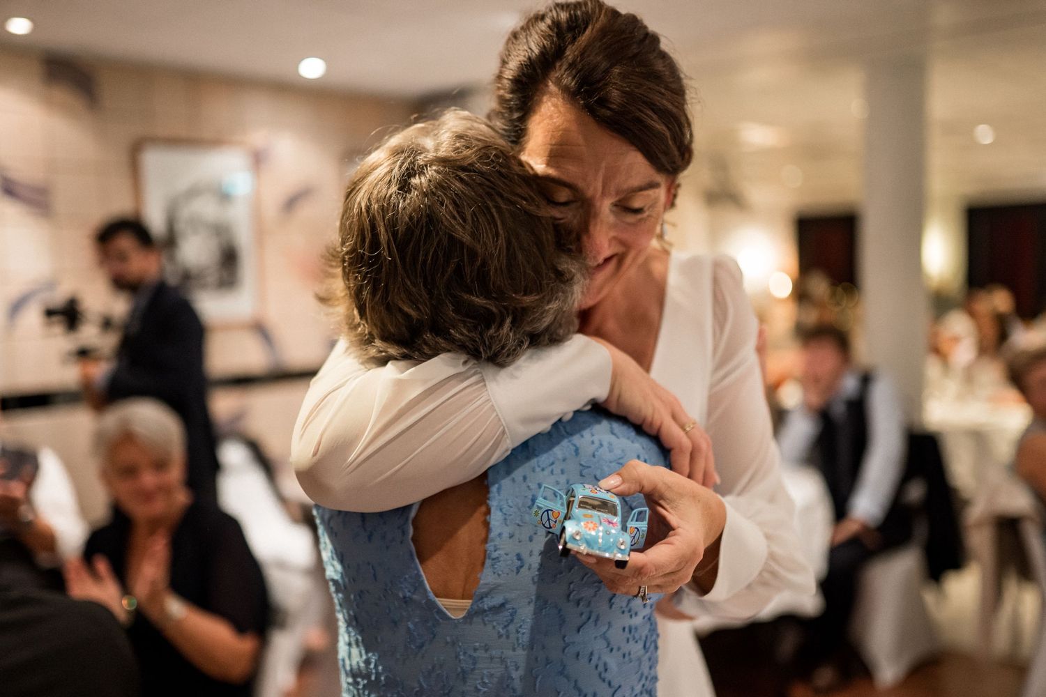 Candid moments of wedding guests hugging during reception celebrations.