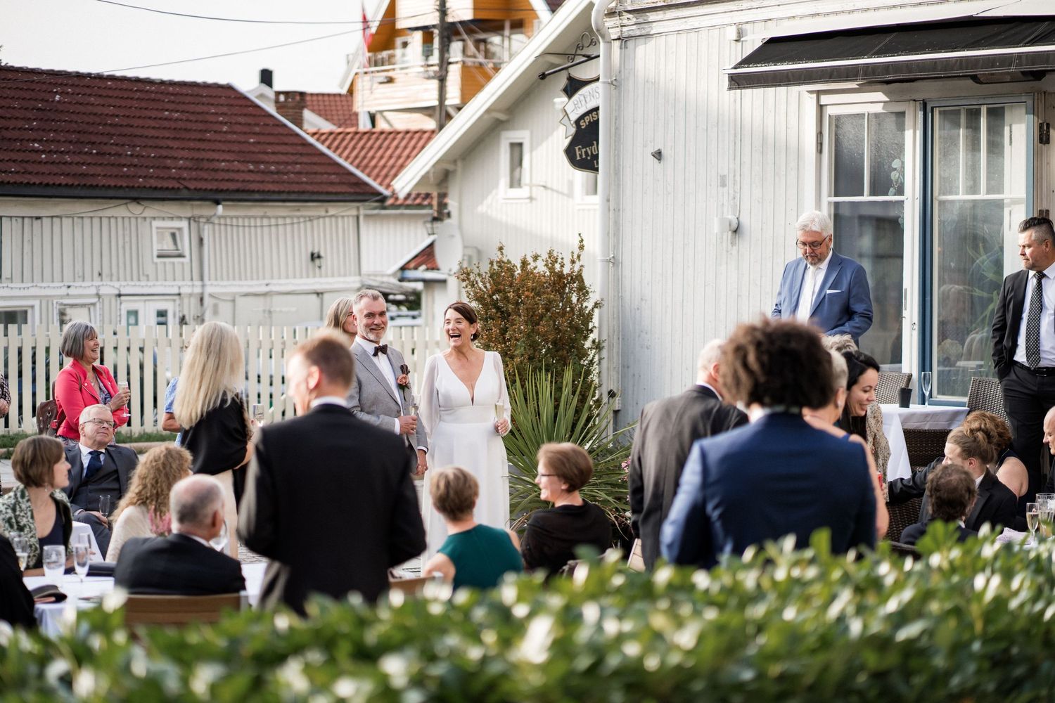 Guests gathering outside white buildings during an outdoor event.