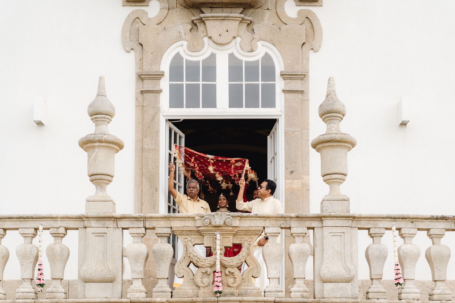 Ornate white stone balcony decorated for an elegant outdoor wedding ceremony.