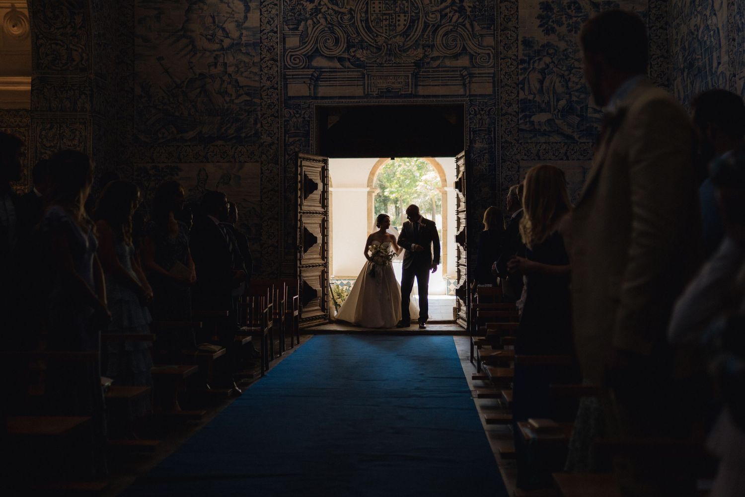 Silhouetted figures in a dark archway during a wedding ceremony.