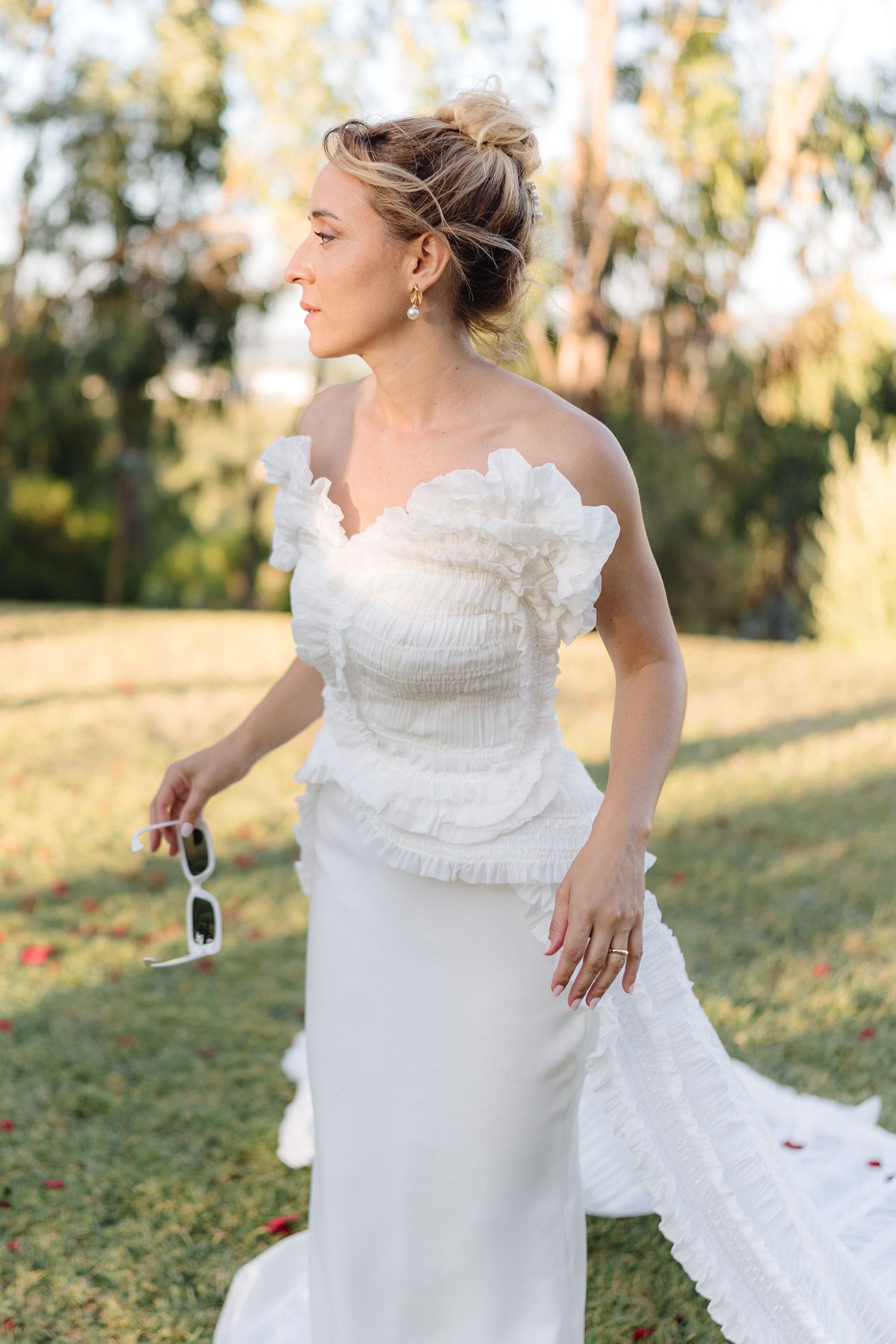 Elegant white wedding dress with ruffled details captured in outdoor setting.