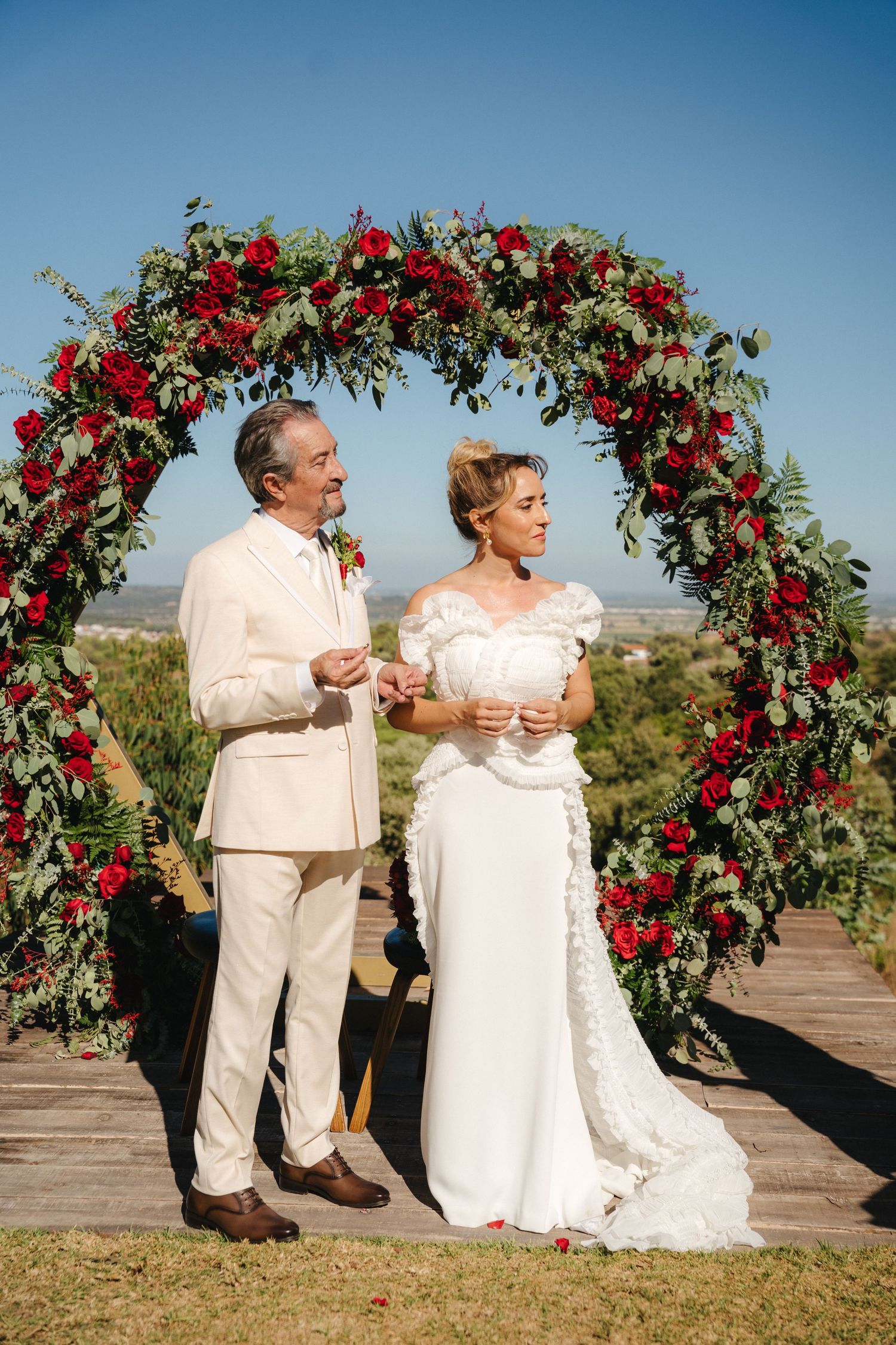 Couple shares a special moment during their wedding ceremony under an ornate floral arch.