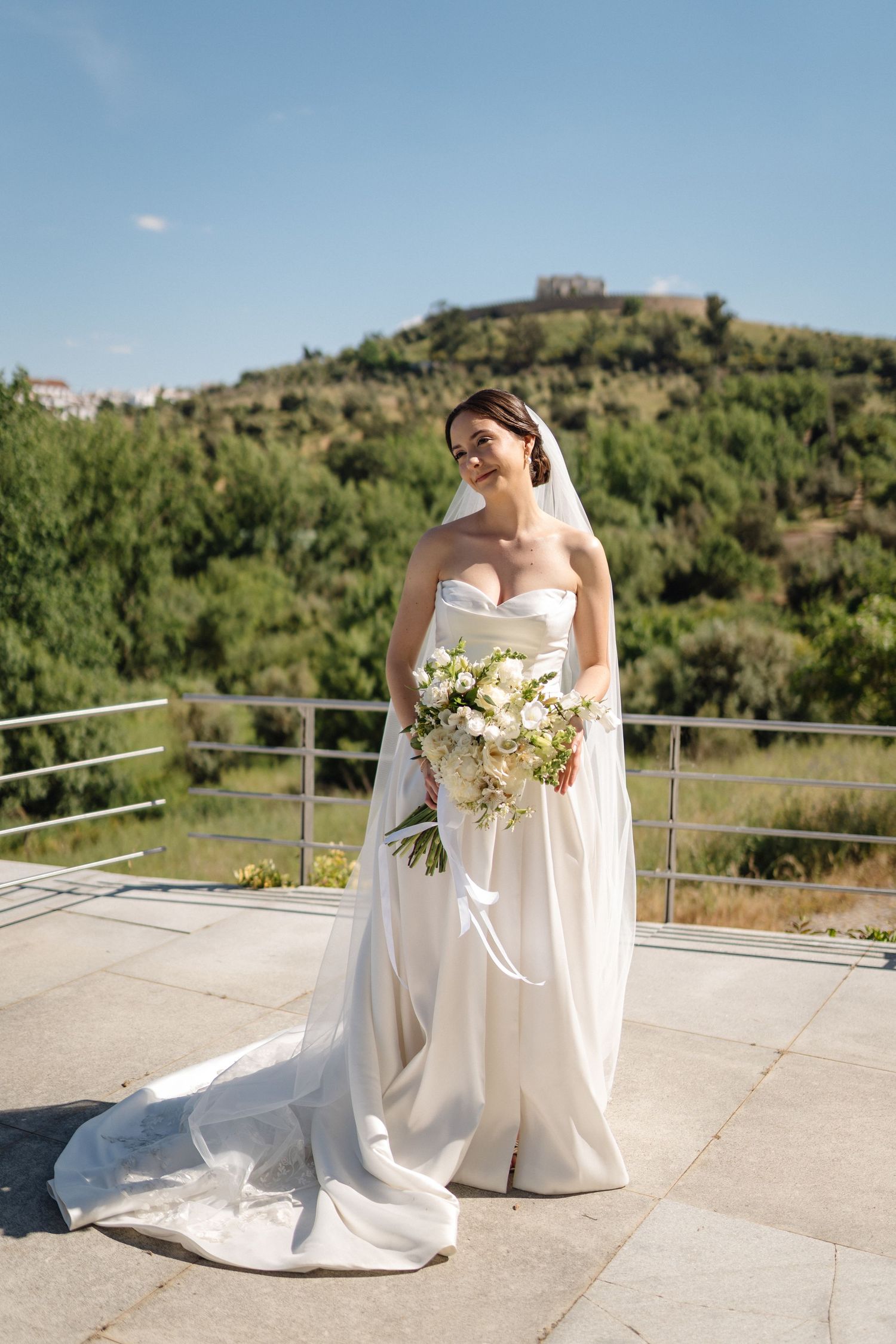 Elegant bridal moment captured on outdoor terrace with mountainous backdrop.