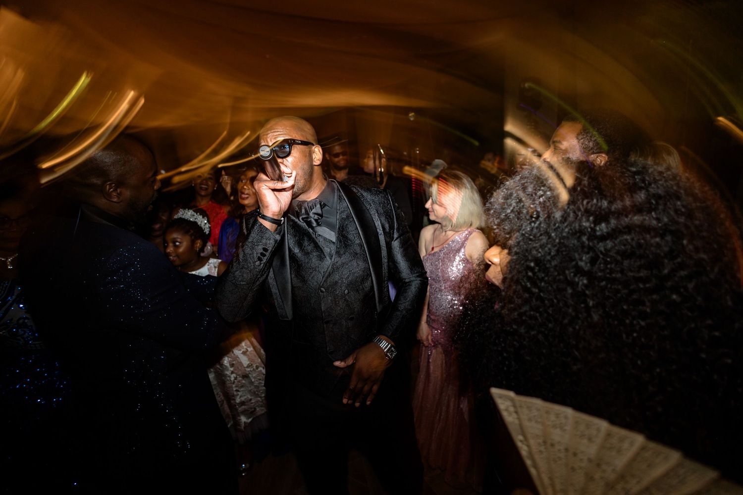 Guests dancing and celebrating at a dimly lit wedding reception.