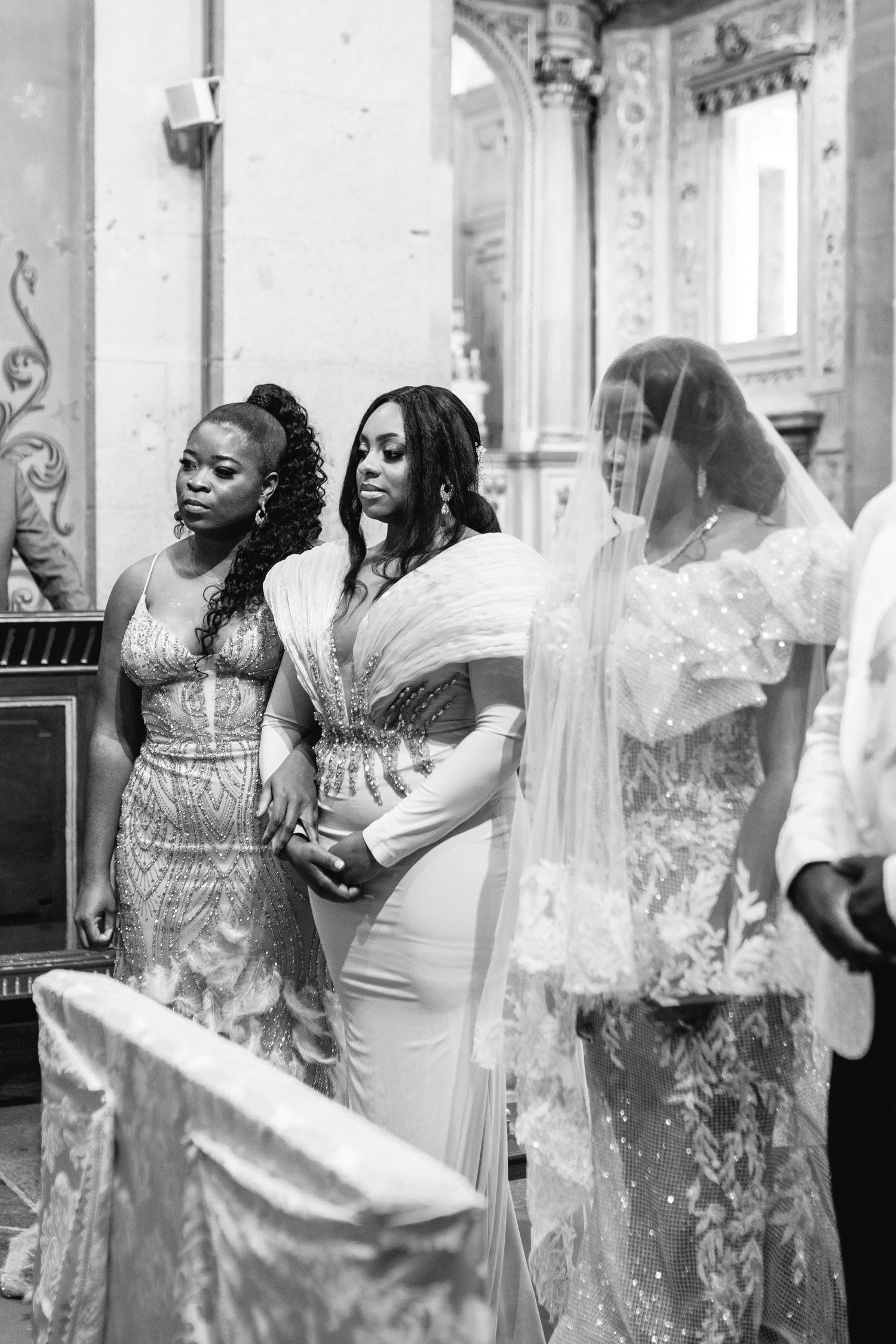 Wedding party members dancing and celebrating in formal attire at an ornate indoor venue.