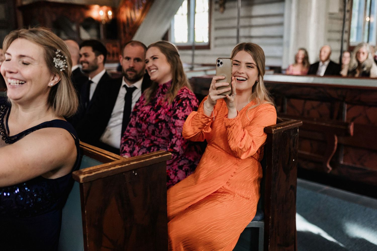 Wedding guests enjoying festivities in a warm-lit venue with orange accents.