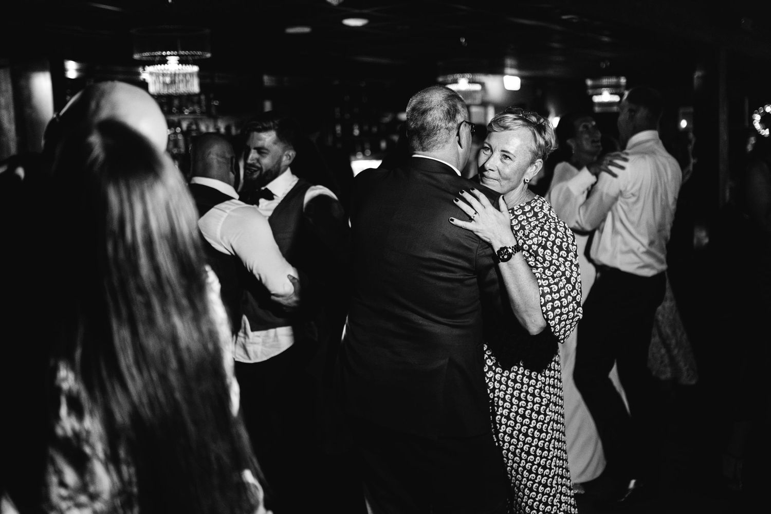 Dark reception venue with guests dancing and celebrating.