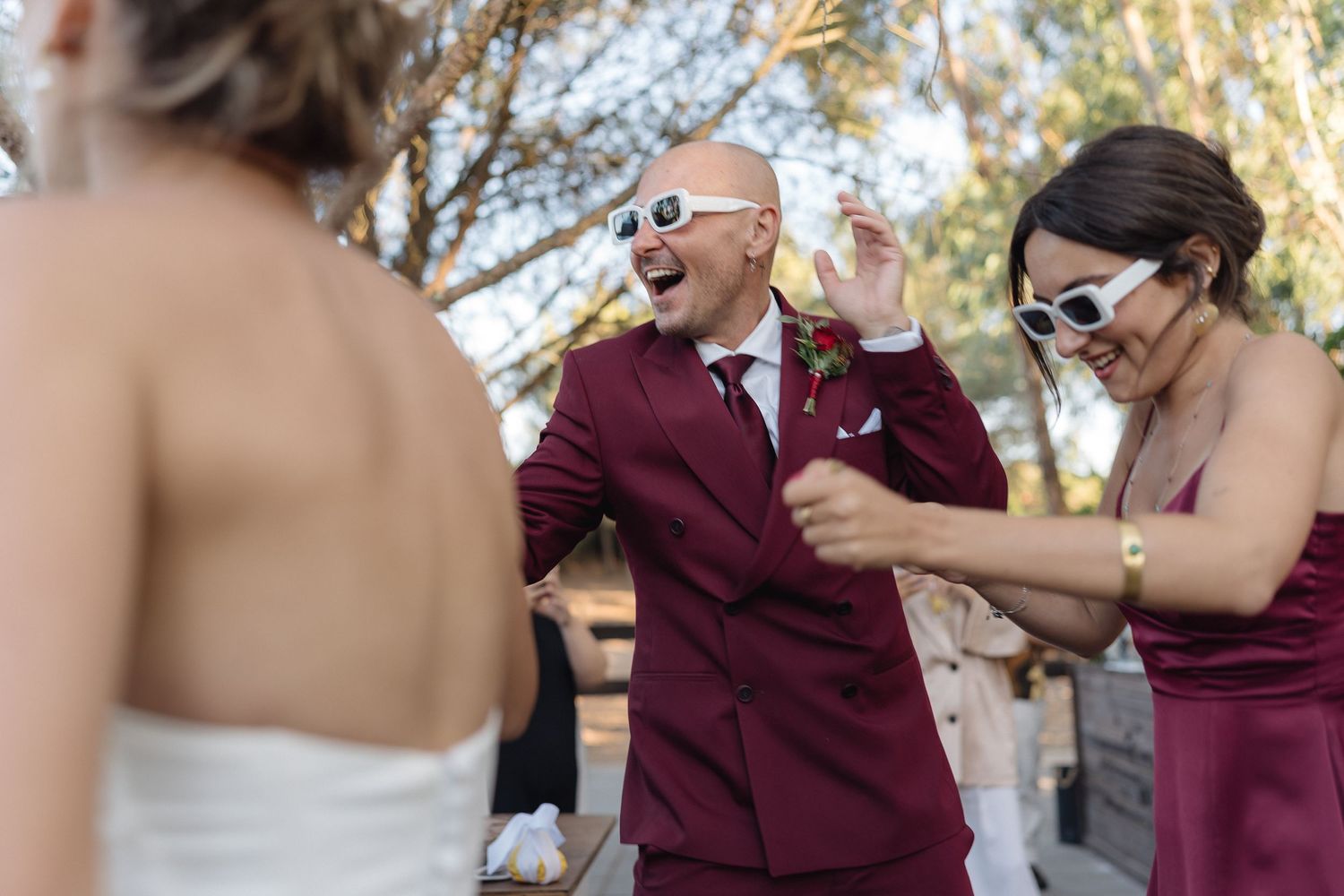 Wedding guests react with surprise and joy during an outdoor celebration.