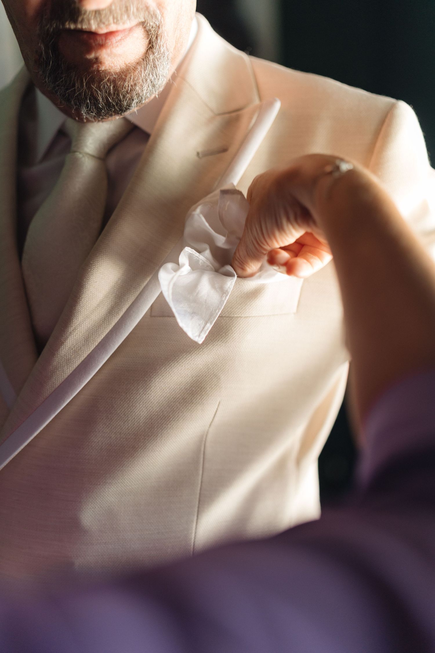 Close-up details of a white suit jacket in soft lighting.