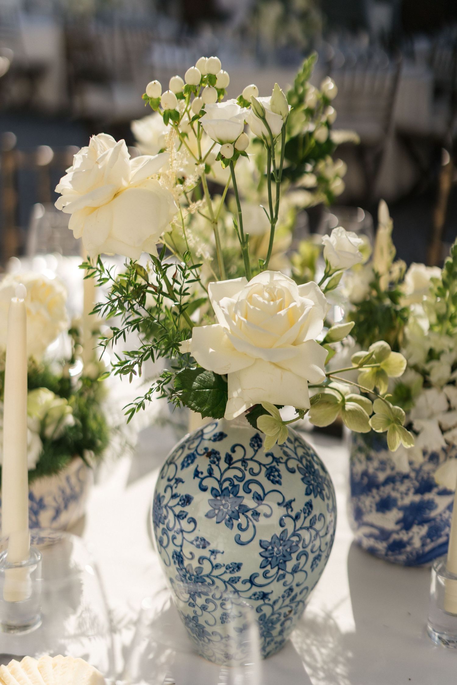 White roses and delicate flowers arranged in a blue and white chinoiserie vase.
