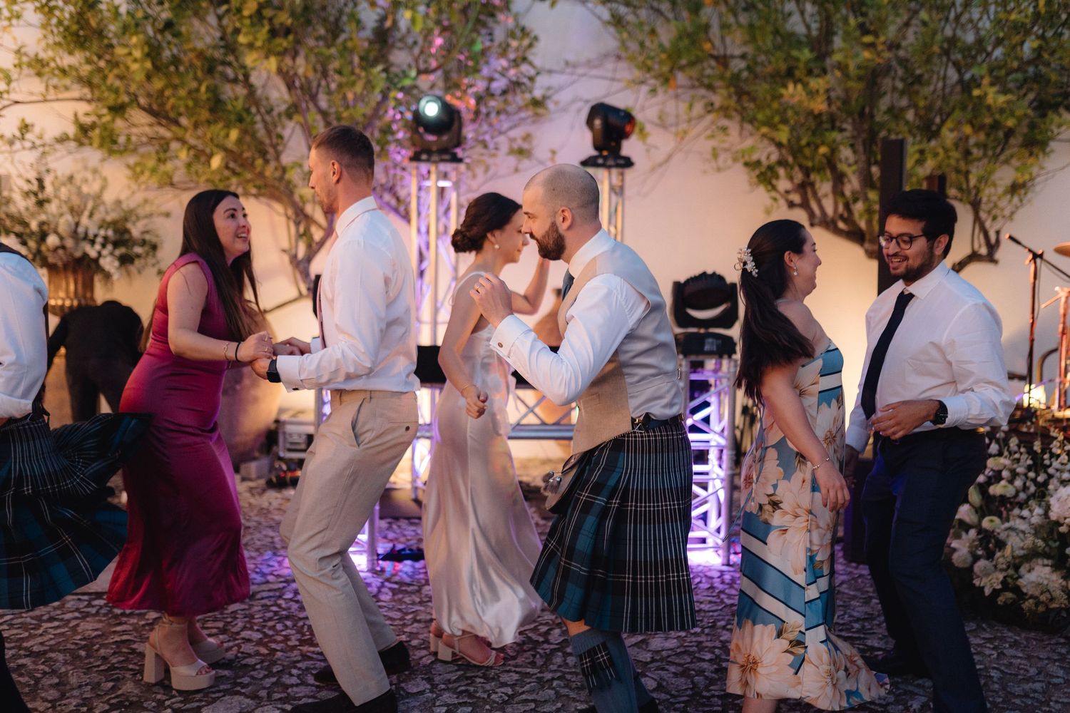 People dancing and celebrating at a festive outdoor evening party.