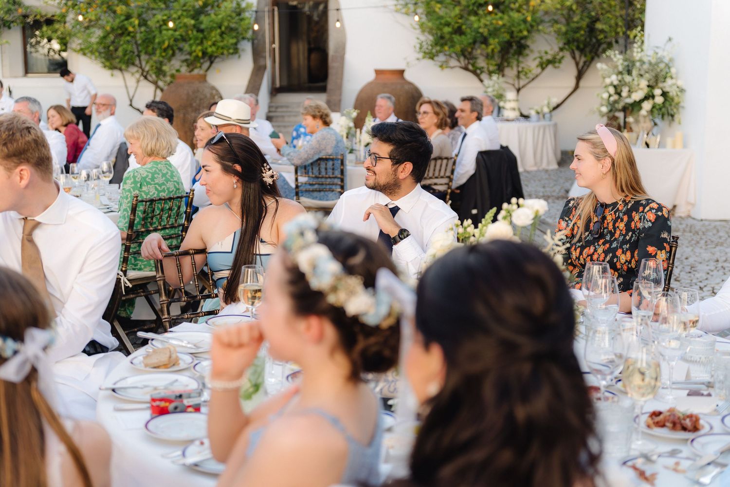 Outdoor wedding reception tables set with white linens and floral centerpieces in a courtyard setting.