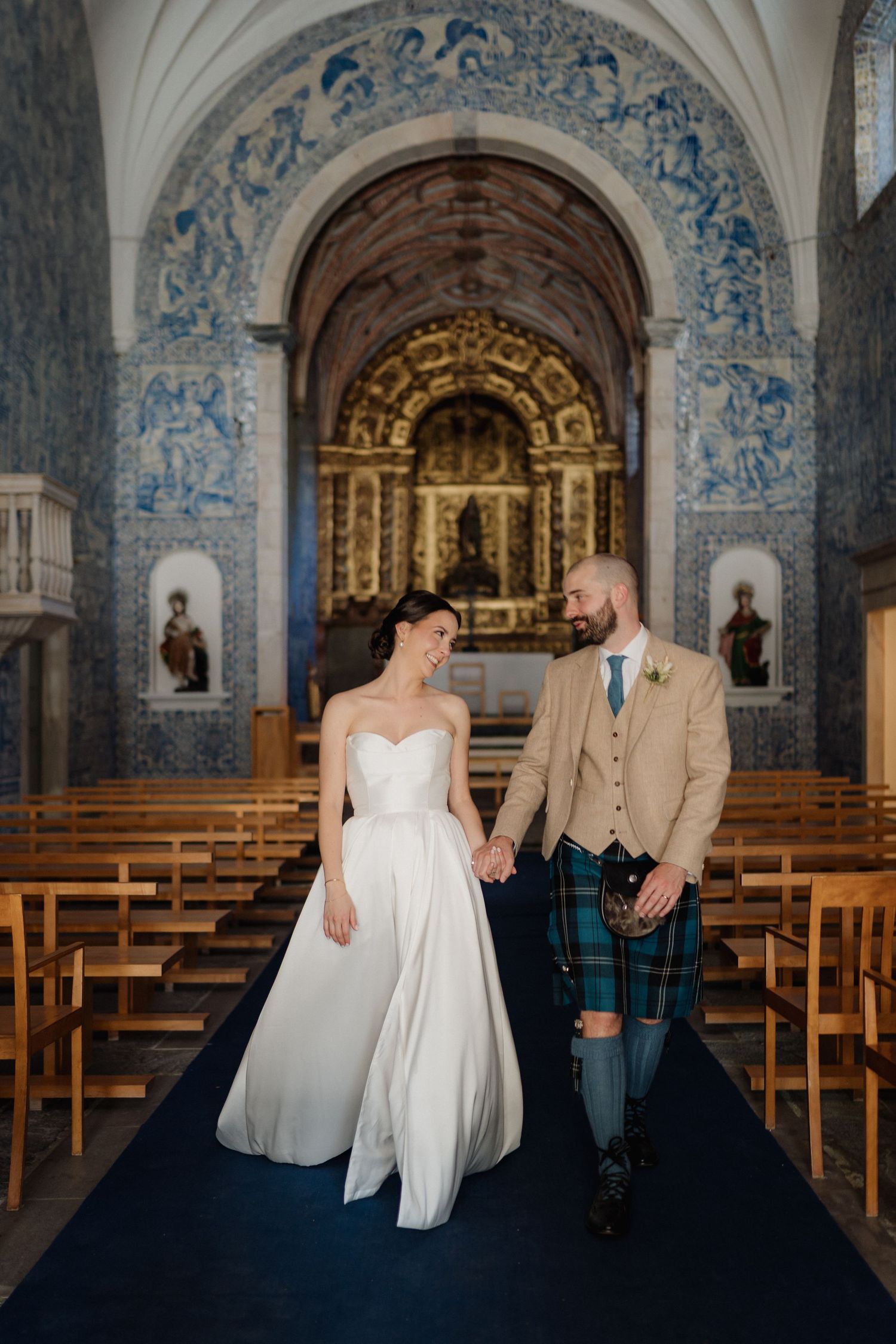A romantic wedding ceremony in a historic church with blue and white tile walls and wooden pews.
