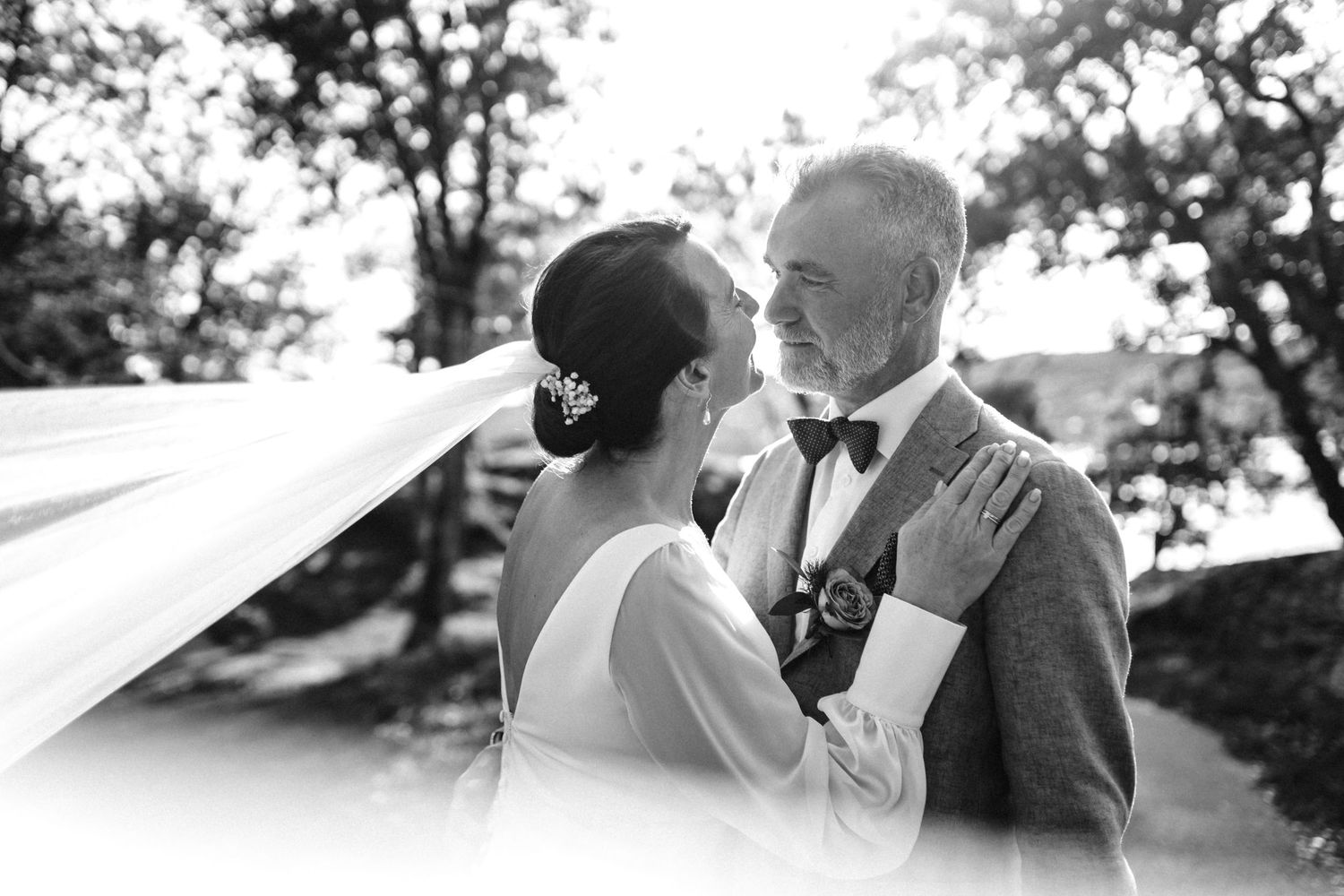 Black and white romantic moment captured between couple during outdoor wedding.