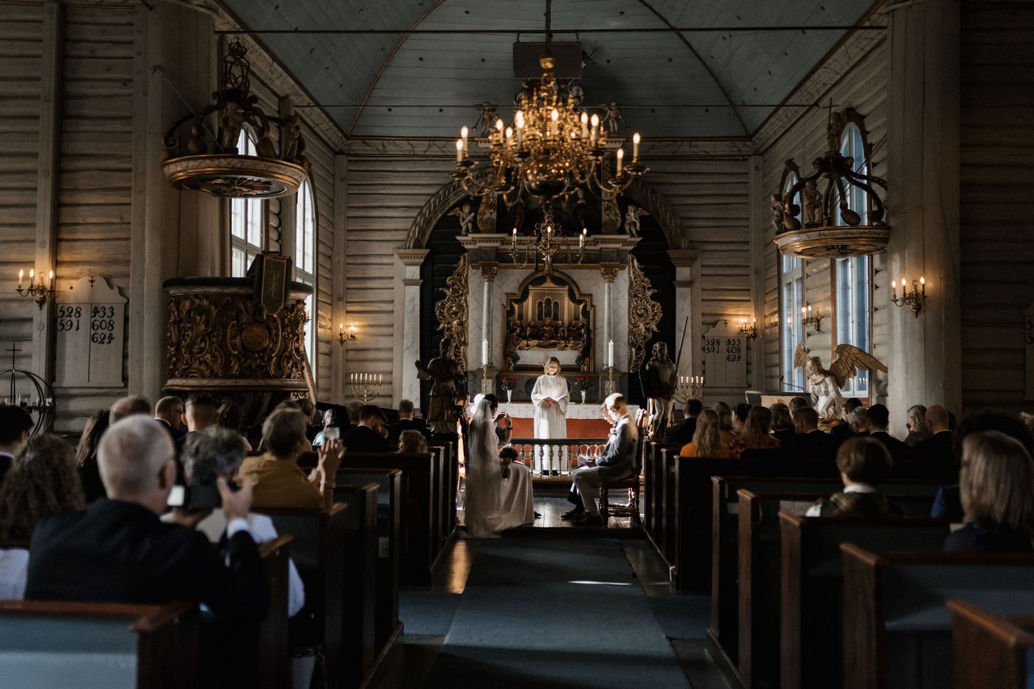 Elegant church interior with chandelier and wooden pews illuminated by natural light.