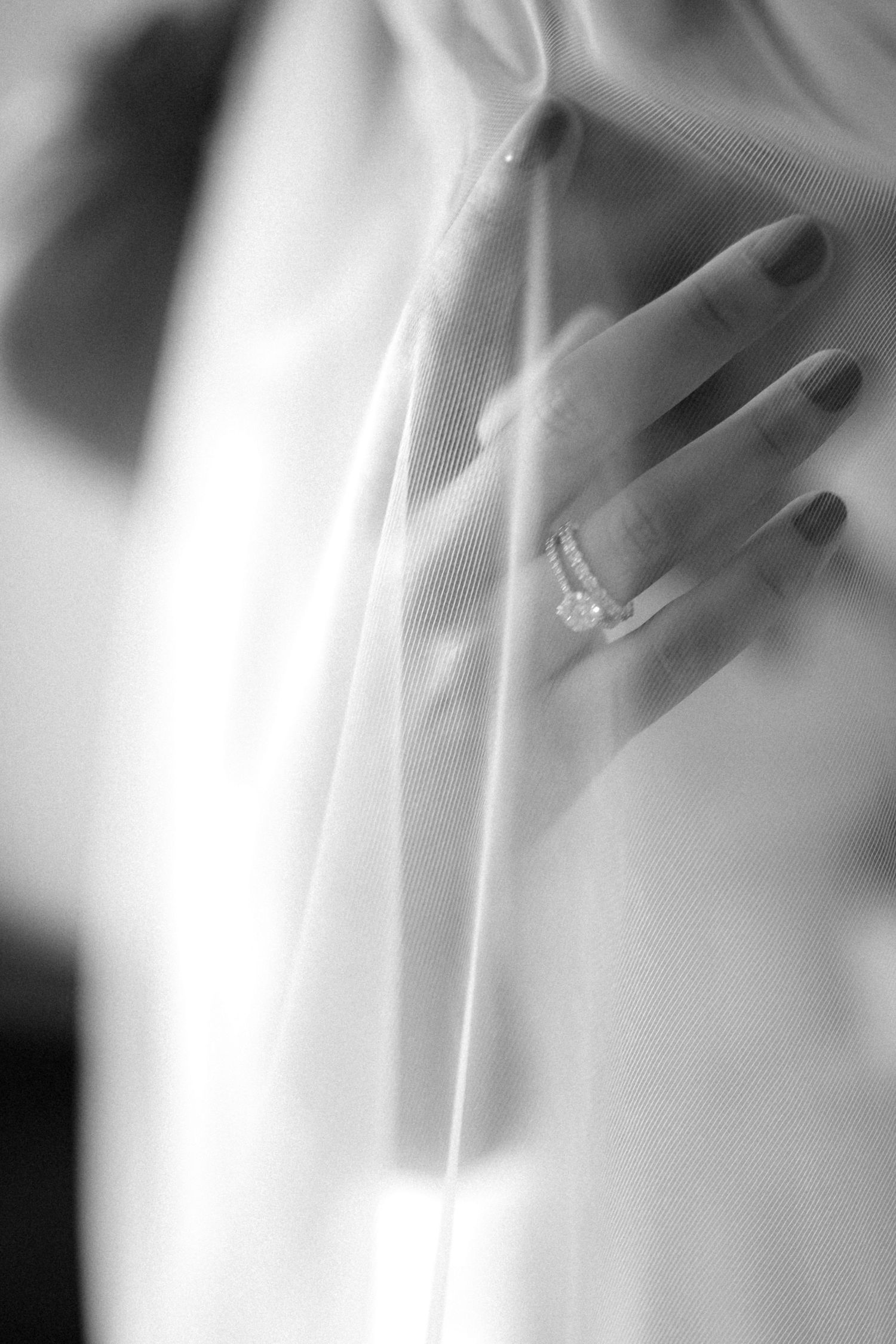 Close-up detail of wedding ring and delicate lace in black and white.