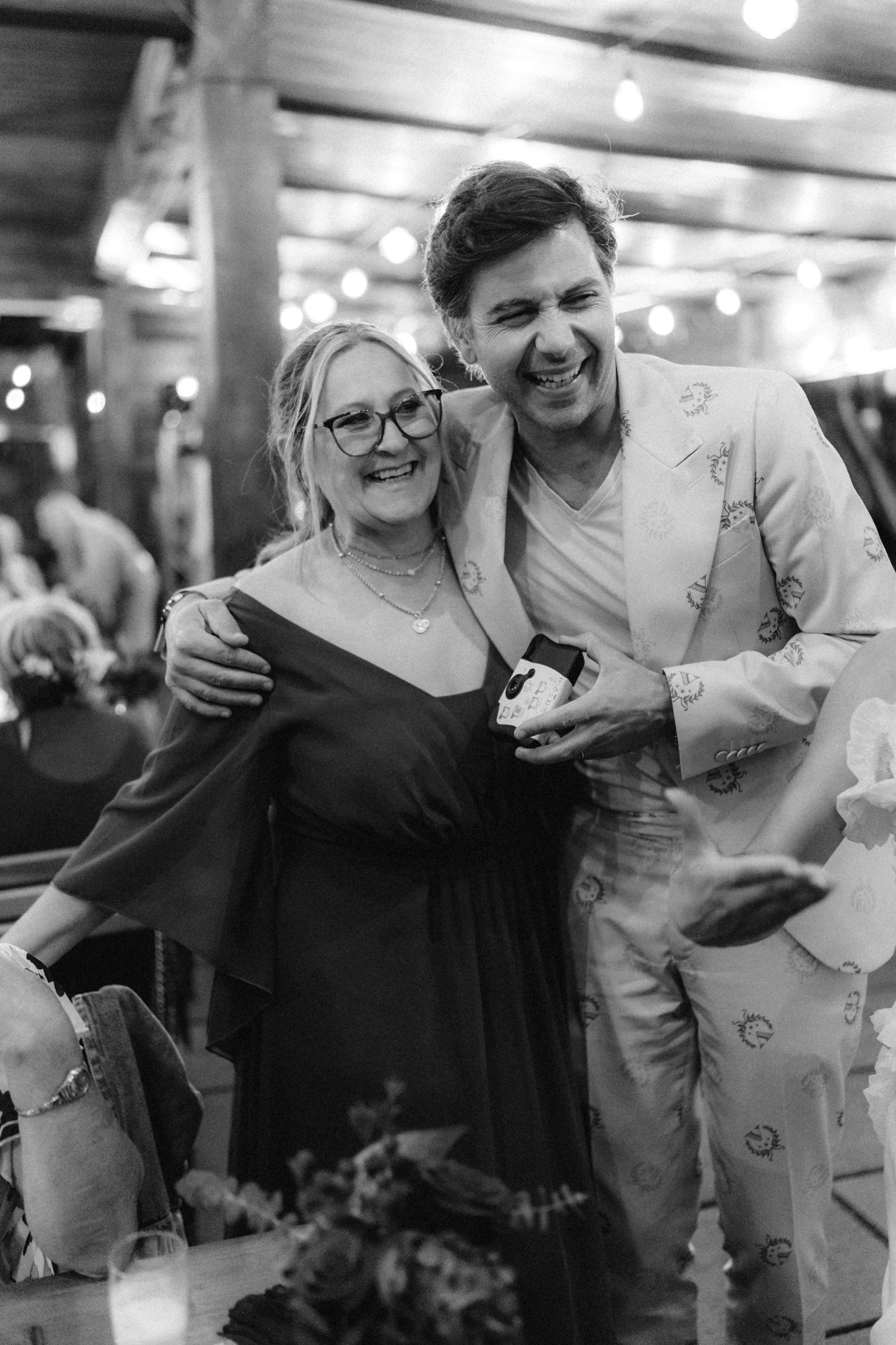 Black and white candid moments from a joyful celebration with people embracing.