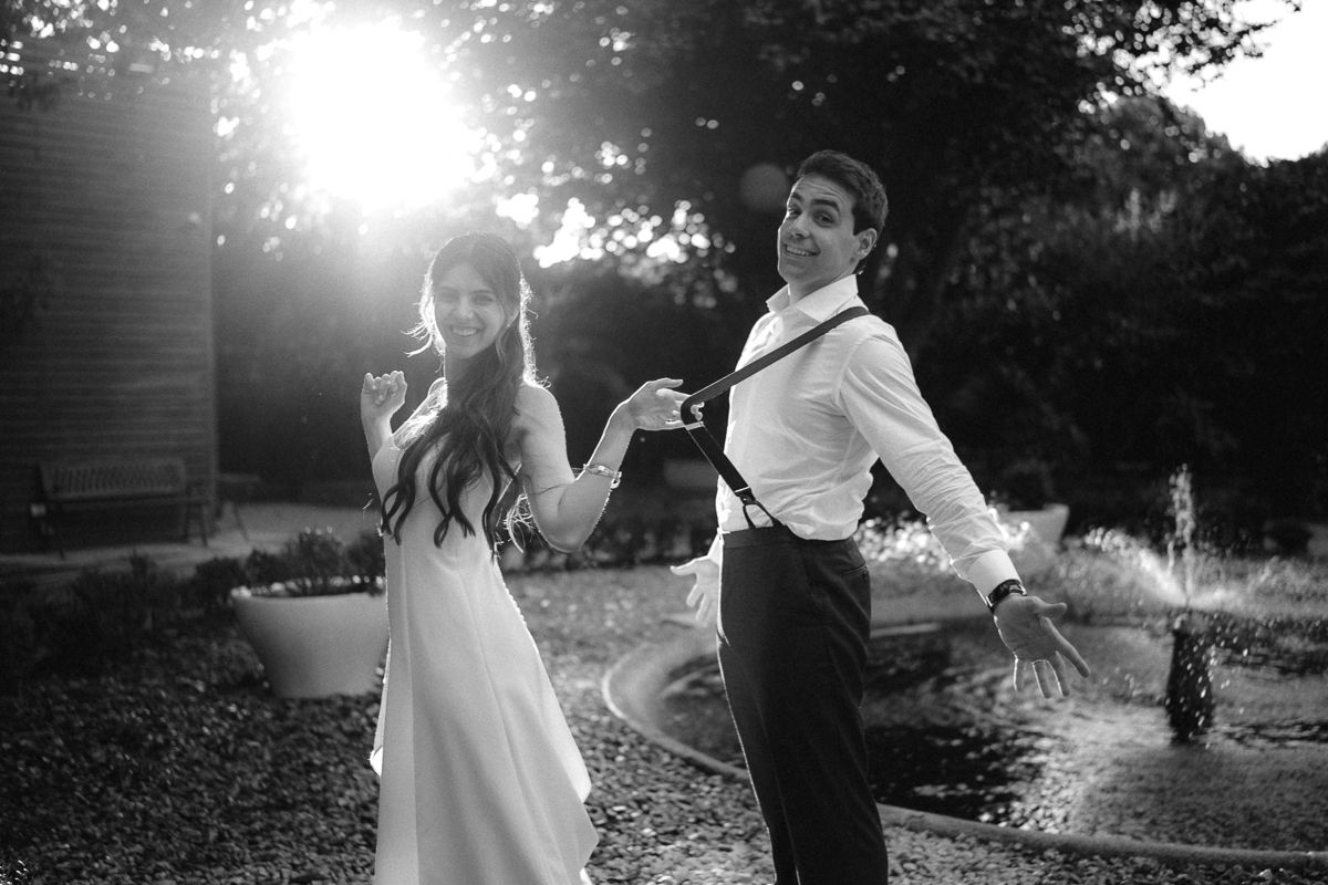 Romantic silhouettes dancing in golden sunlight during an outdoor wedding celebration.