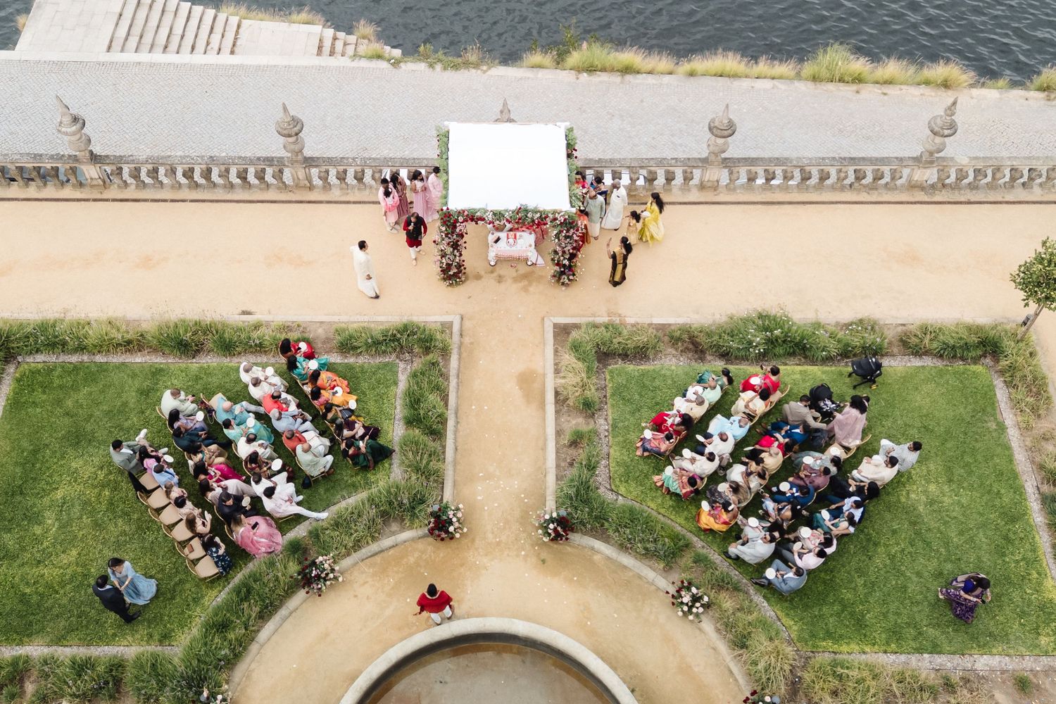 Aerial view of wedding ceremony seating arrangement on manicured lawn of historic venue.