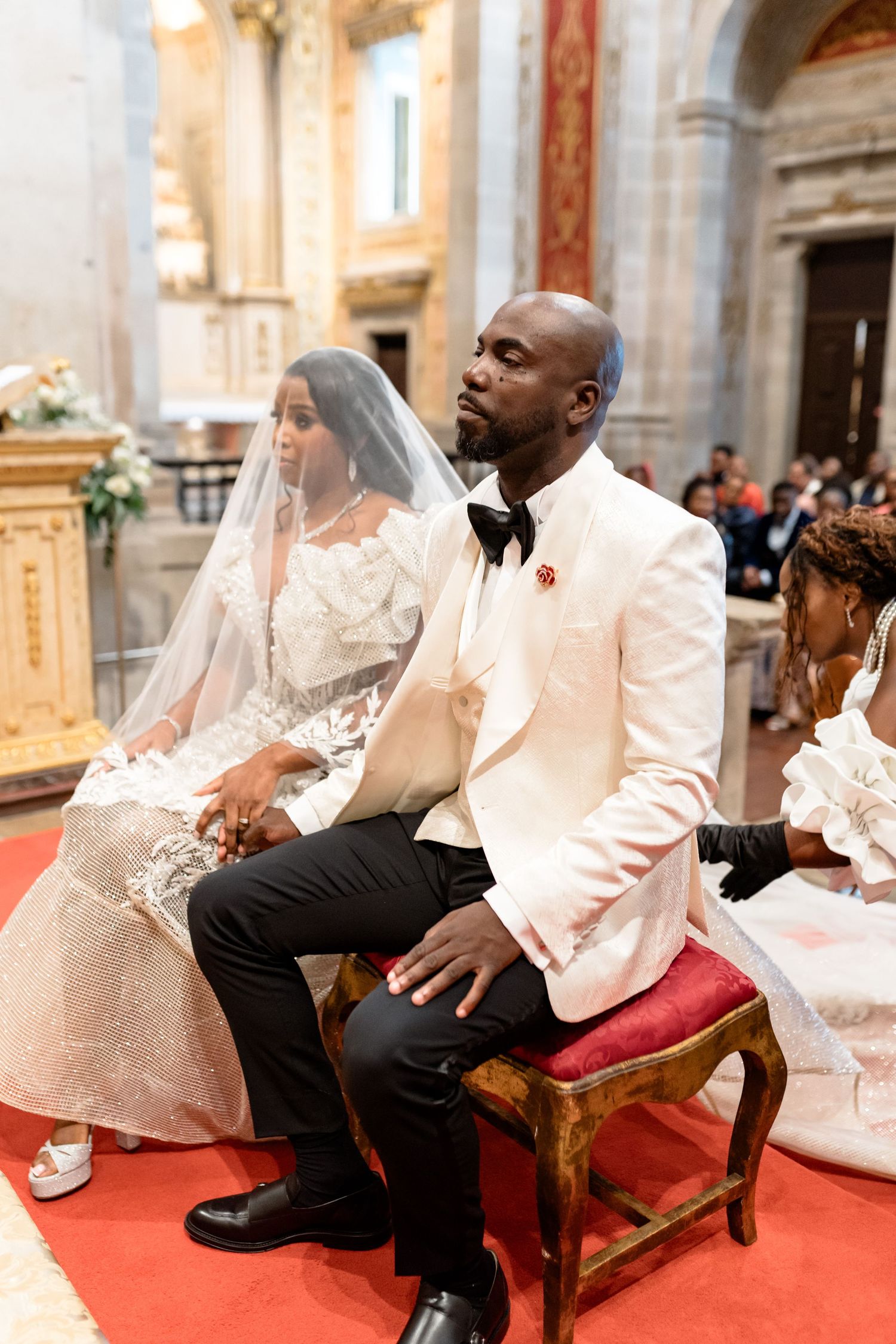 Wedding ceremony in ornate church with red carpet and decorative interior.