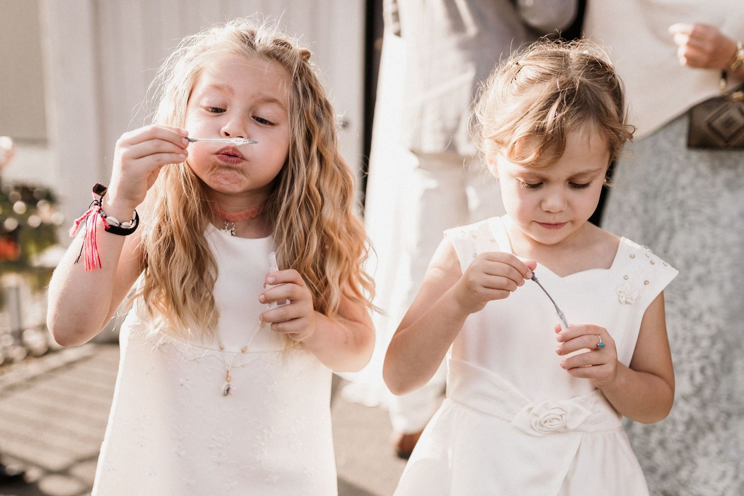 Young children in white dresses enjoying treats at a celebration.